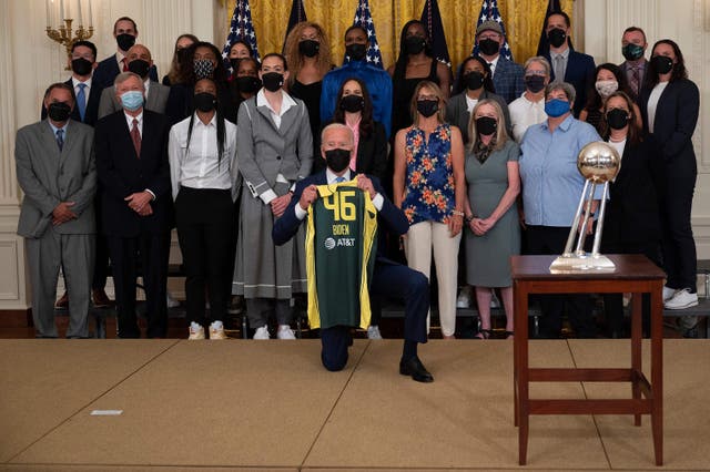 <p>US President Joe Biden holds a jersey as he poses with Seattle Storm Players during an event at the White House in Washington, DC, on August 23, 2021</p>