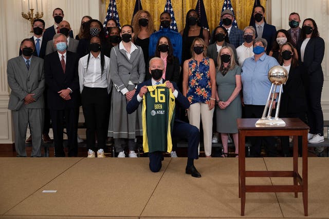 <p>US President Joe Biden holds a jersey as he poses with Seattle Storm Players during an event at the White House in Washington, DC, on August 23, 2021</p>