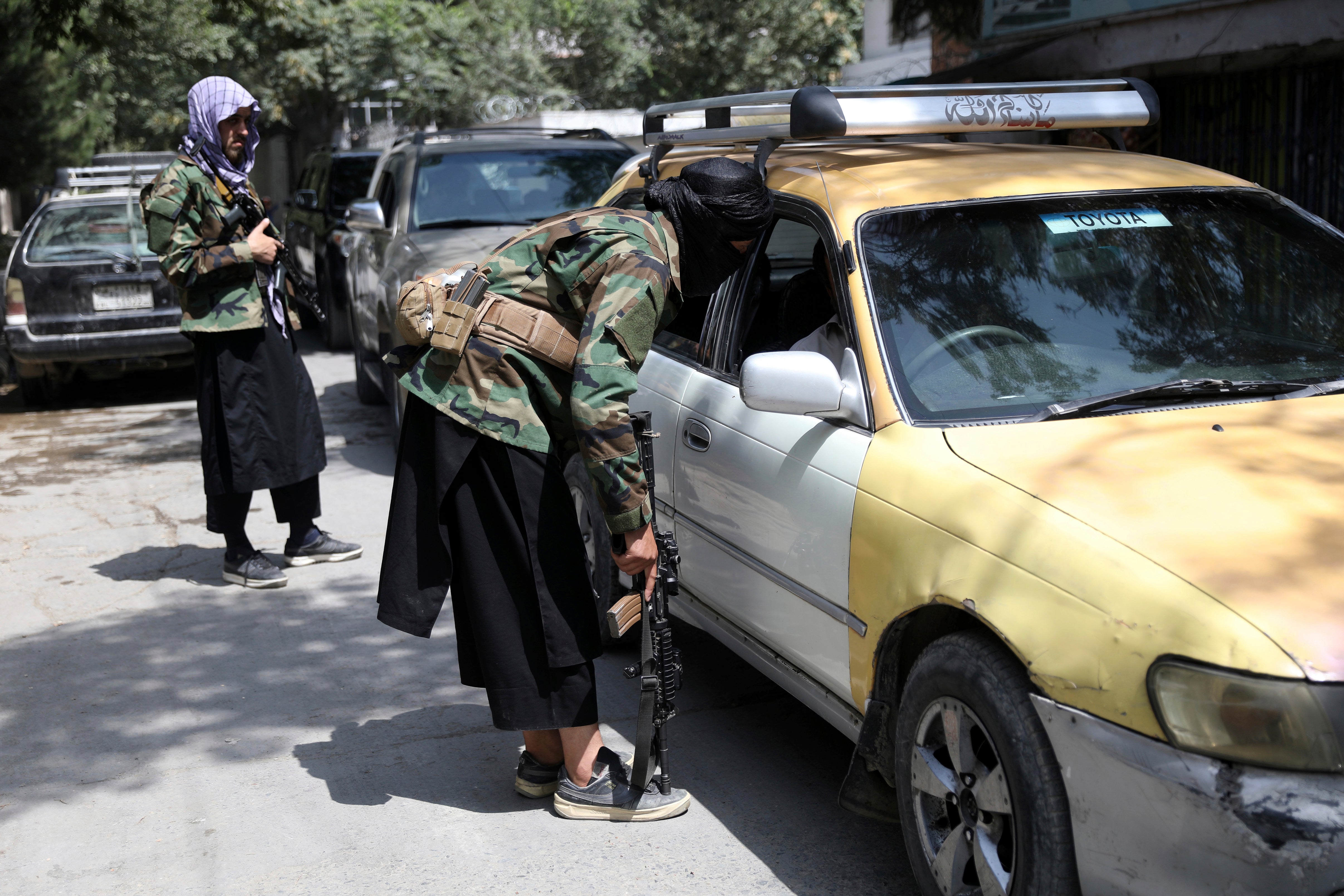 In this 22 August 2021 file photo, Taliban fighters search a vehicle at a checkpoint on the road in the Wazir Akbar Khan neighbourhood in the city of Kabul, Afghanistan