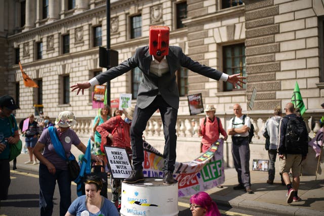 <p>A man wearing a petrol can joins climate activists from XR outside the offices of HM Revenue and Customs</p>
