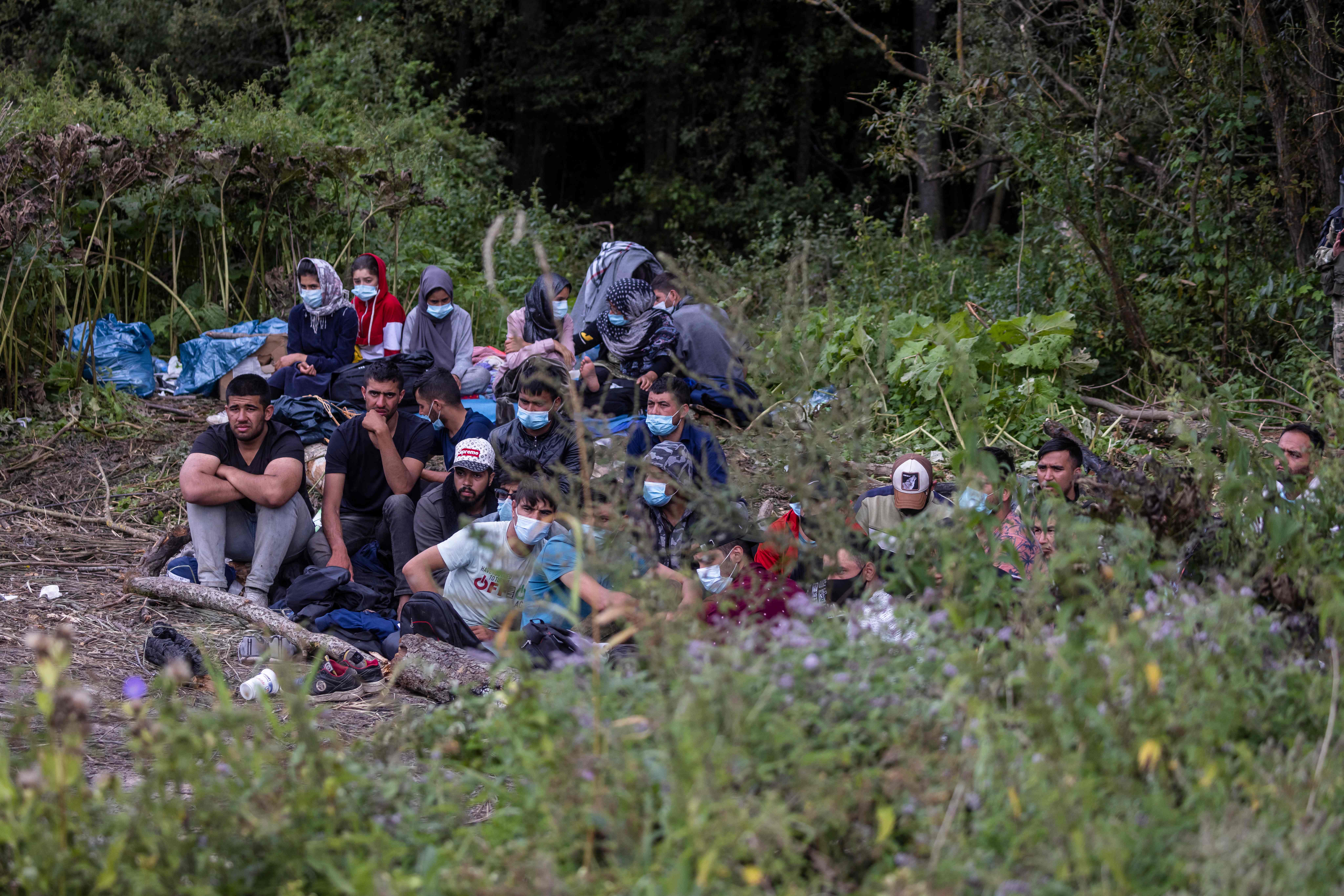 Migrants believed to be from Afghanistan sit at the border between Belarus and Poland near the village of Usnarz Gorny on 20 August 2021