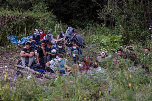 <p>Migrants believed to be from Afghanistan sit at the border between Belarus and Poland near the village of Usnarz Gorny on 20 August 2021</p>