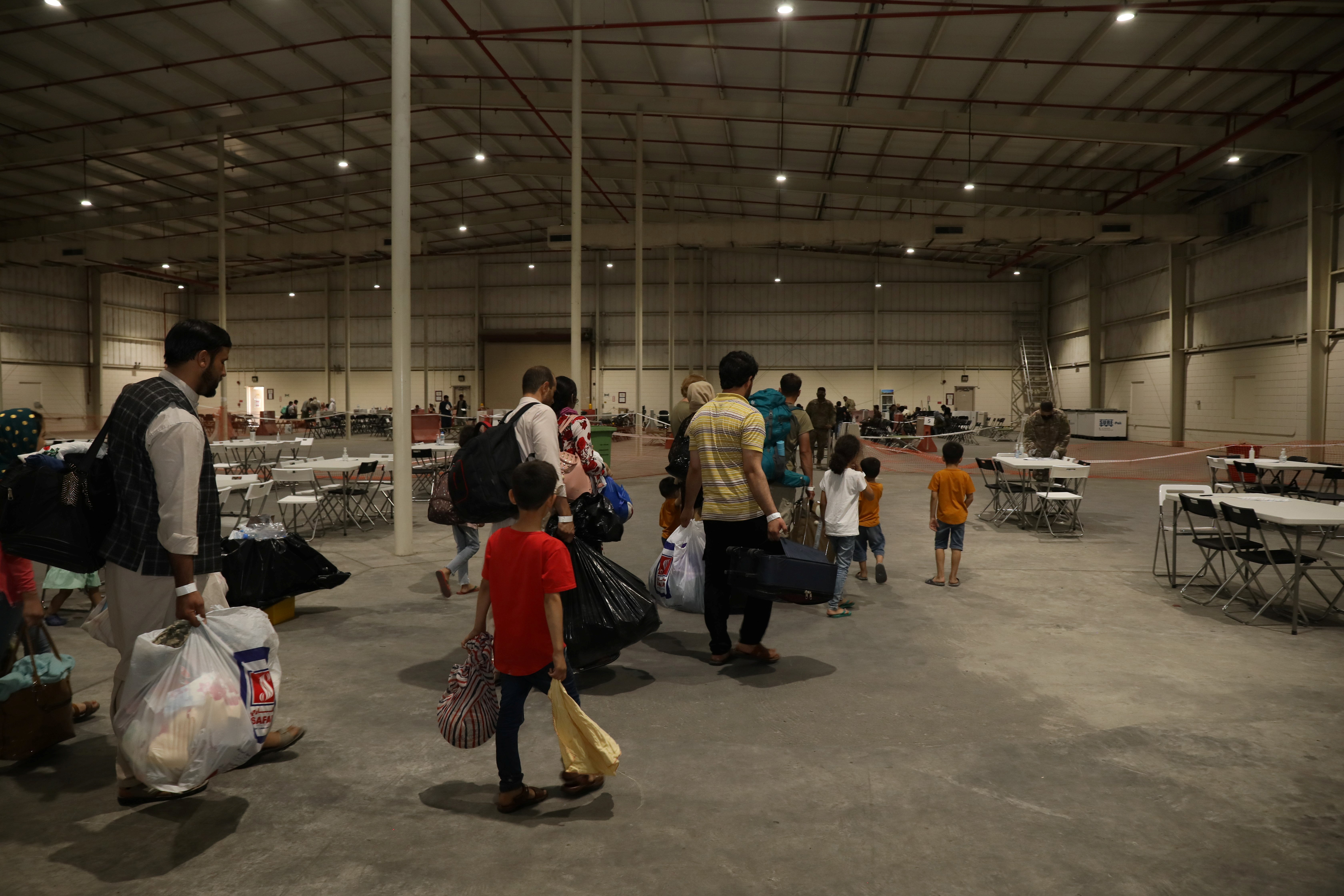 Special Immigrants from Afghanistan walk through the in-processing building after their evacuation at Camp As Sayliyah, Qatar, August 20, 2021.