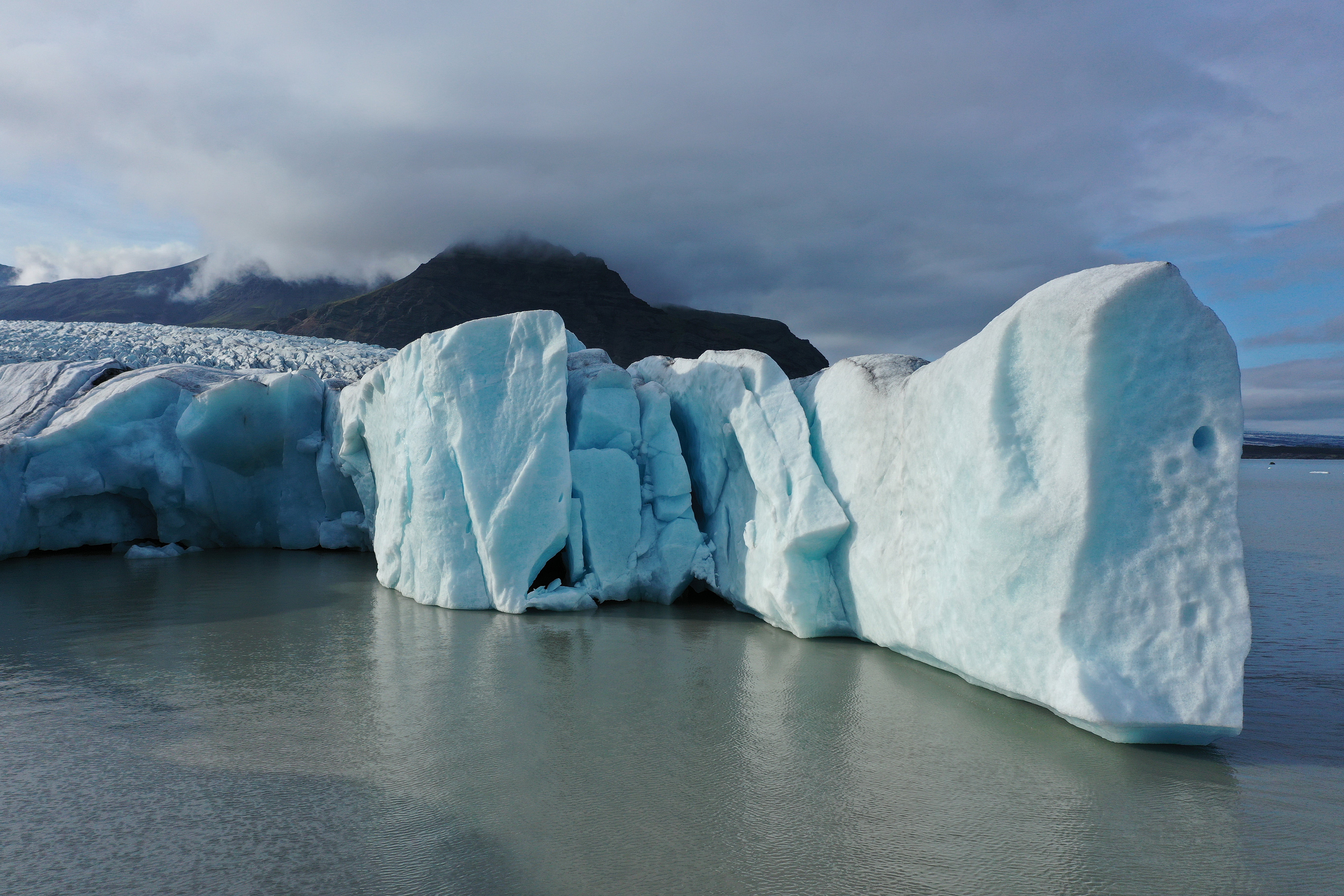 Piezas de la cara que se derrite del glaciar Fjallsjokull se adentran en un lago del propio agua de deshielo del glaciar el 14 de agosto de 2021 cerca de Hof, Islandia
