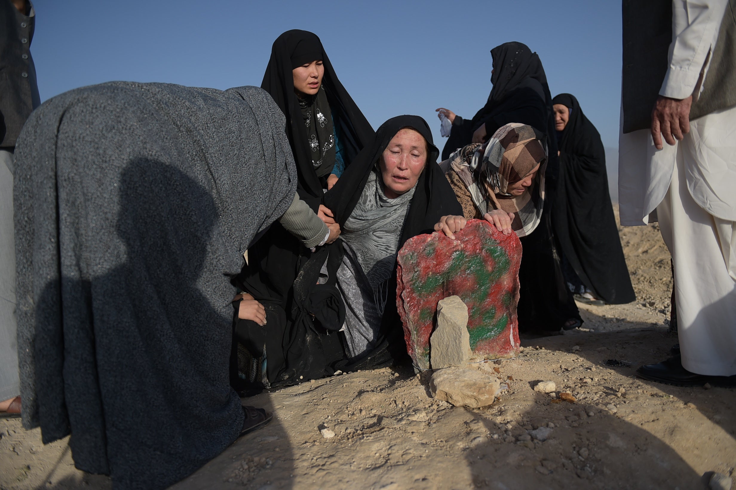 An elderly mother mourns at the grave of her Hazara son after he was killed in the 23 July twin suicide attack in Kabul in 2016