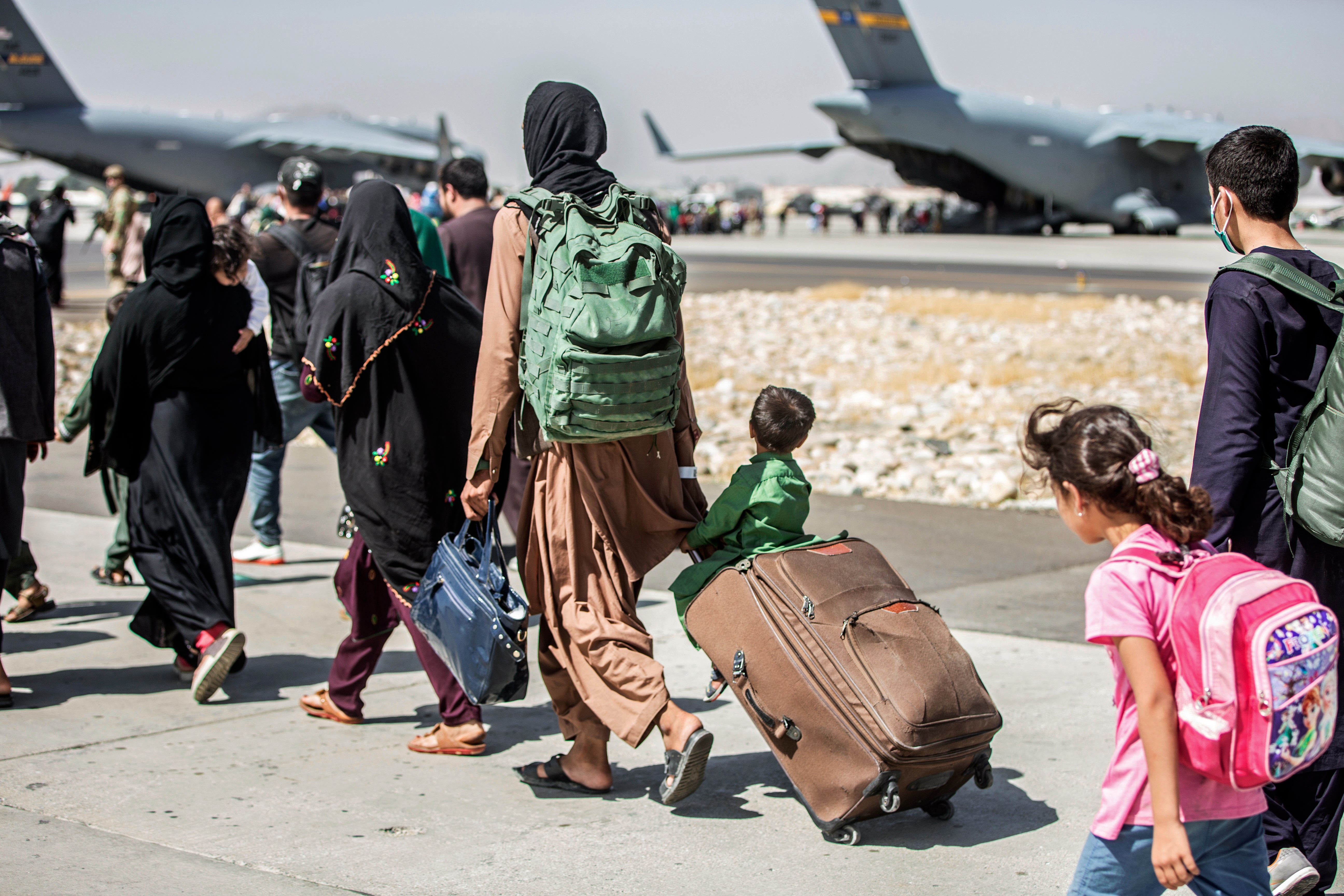 Families walk towards their flight during ongoing evacuations at Hamid Karzai International Airport, in Kabul, Afghanistan