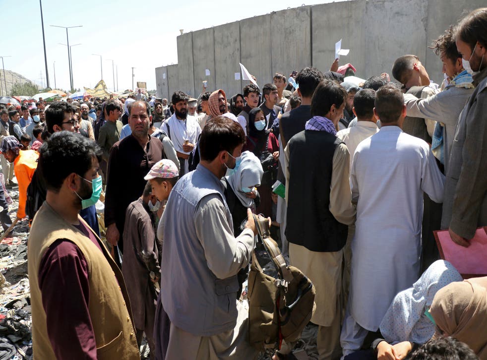 <p>Hundreds of people, some holding documents, gather near an evacuation control checkpoint at  Kabul airport</p>