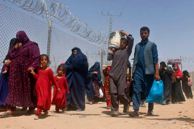 <p>Afghans walk through a security barrier as they enter Pakistan through a common border crossing point in Chaman</p>