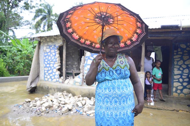 <p>Estabelle stands in front of what is left of her home</p>