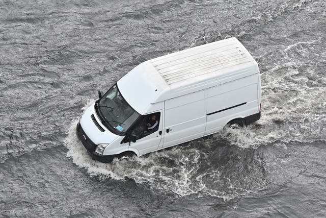 <p>A van drives through water on a flooded road in London</p>