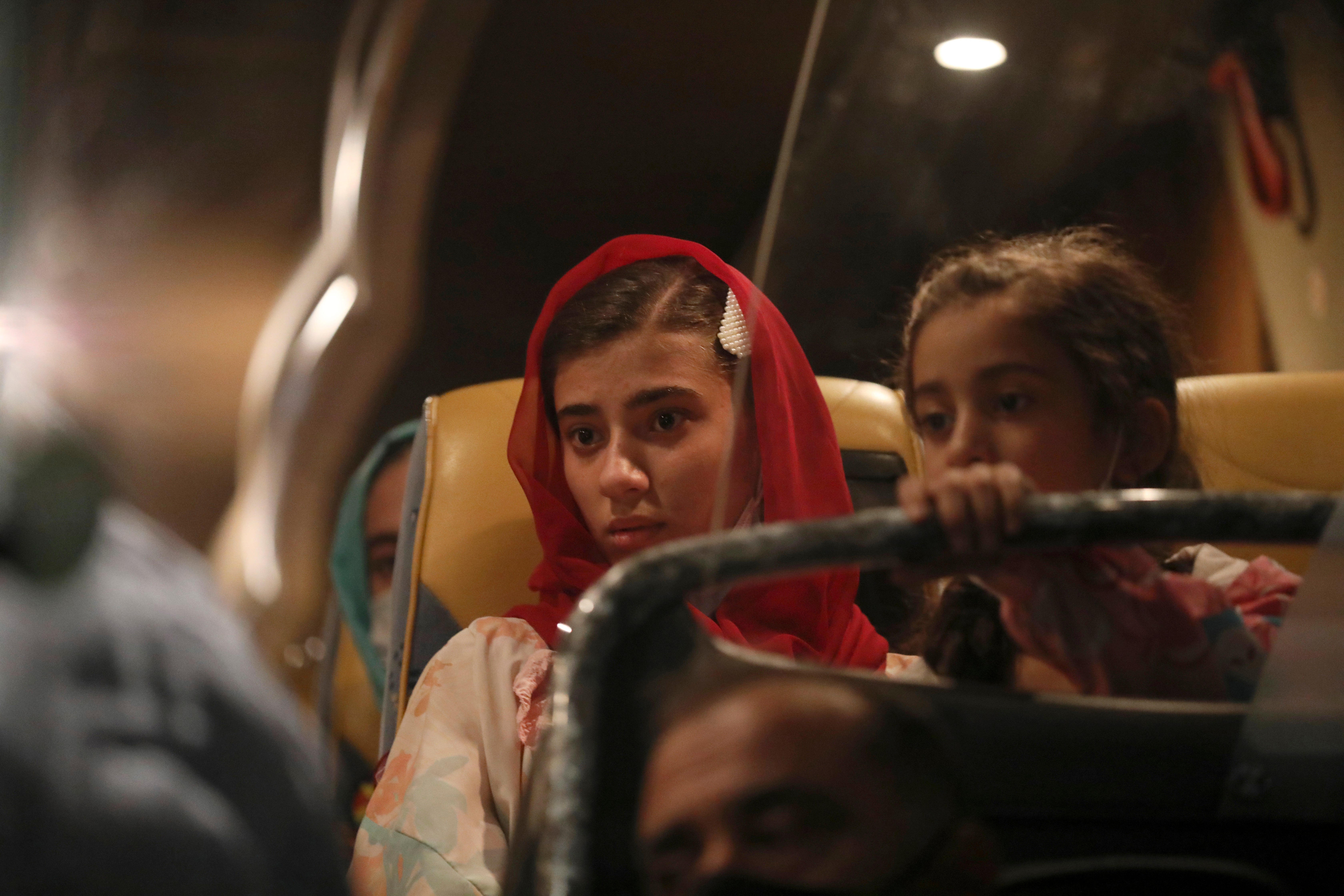 Afghan evacuees from Afghanistan sit in a bus after the arrival of the second flight with 95 passengers at the International Airport in Tirana, Albania