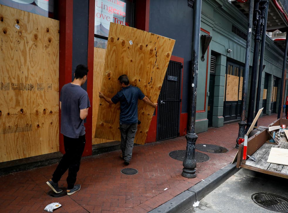 pMen place plywood in front of a store in preparation for Hurricane Ida, in New Orleans/p