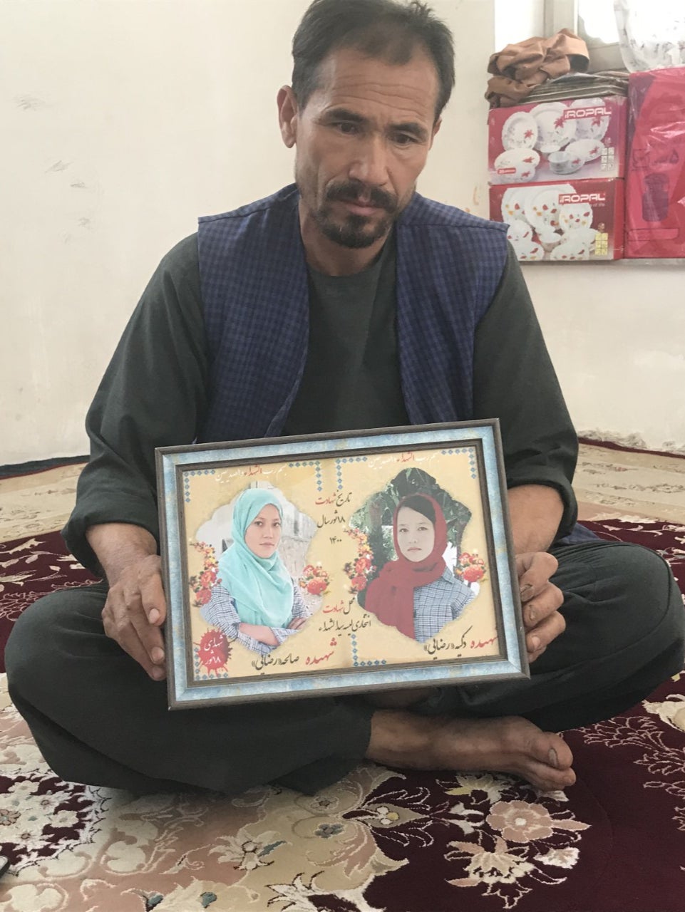 Rajab Ali Razayee holds a picture of his two daughters, who were killed in a school bombing in May