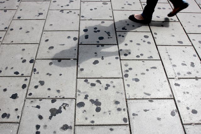 <p>A woman walks by a pavement covered in chewing gum on Oxford Circus in 2008</p>