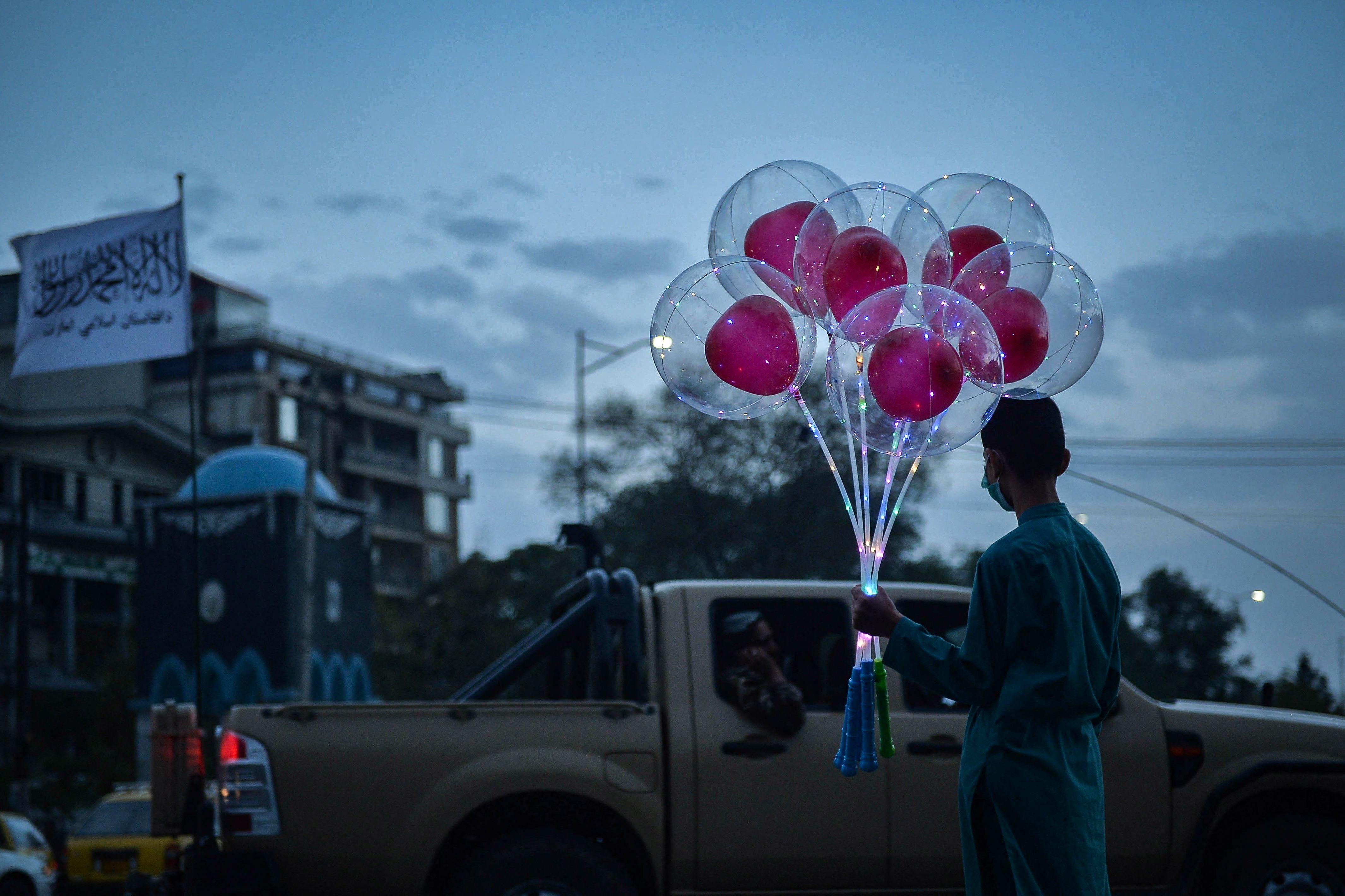 An Afghan boy stands along a road holding a bunch of balloons to sell in Kabul on Monday