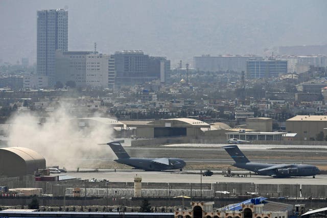 Soldados estadounidenses se paran en la pista mientras un avión de la Fuerza Aérea de los Estados Unidos se prepara para despegar del aeropuerto de Kabul el lunes.