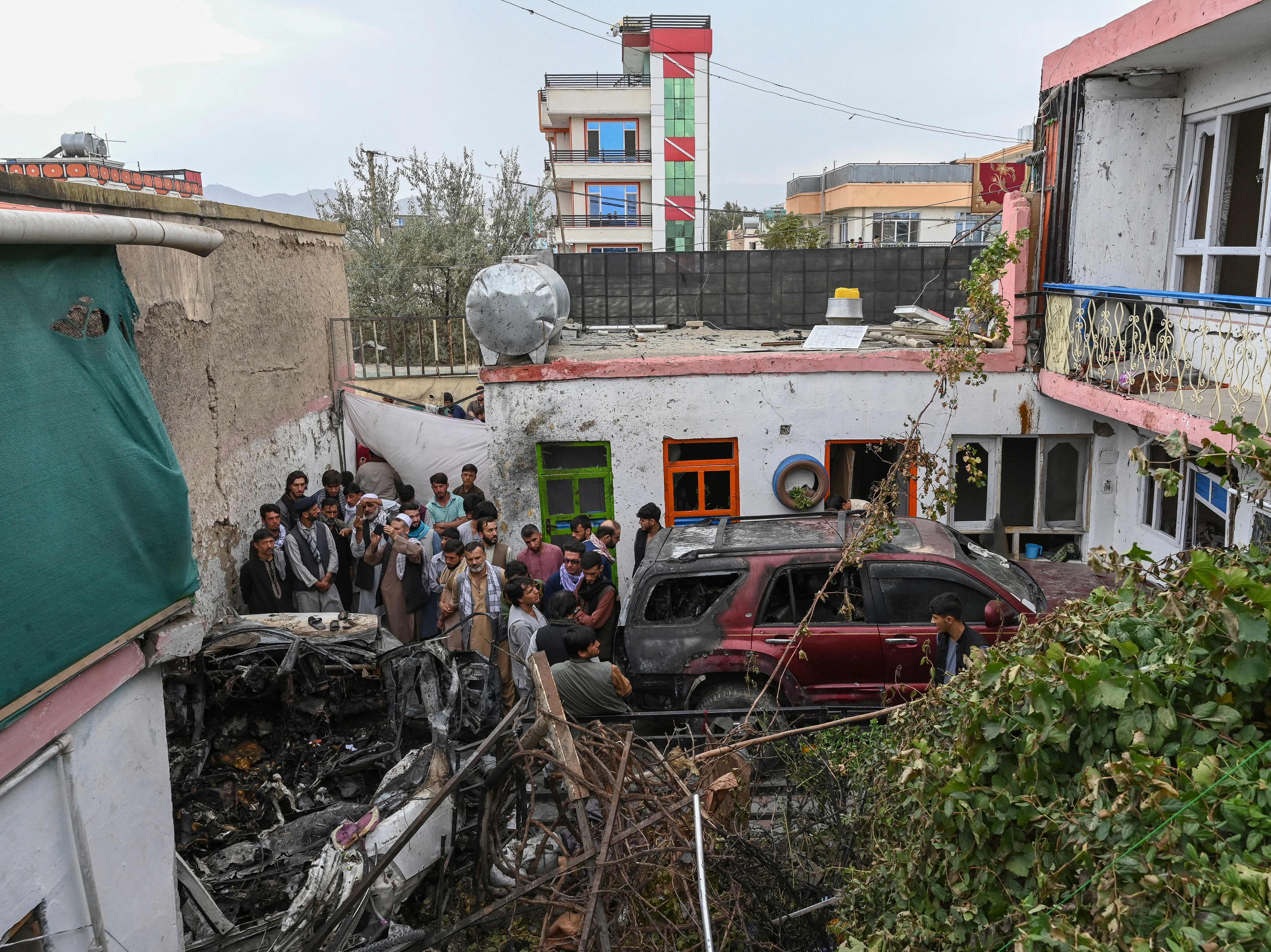 <p>Afghan residents and family members of the victims gather around the damage a day after the US drone strike in Kabul</p>