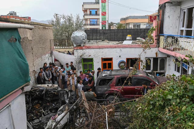 <p>Afghan residents and family members of the victims gather around the damage a day after the US drone strike in Kabul</p>