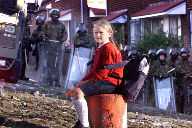 <p>A child waits at army lines to be escorted to Holy Cross school, north Belfast</p>