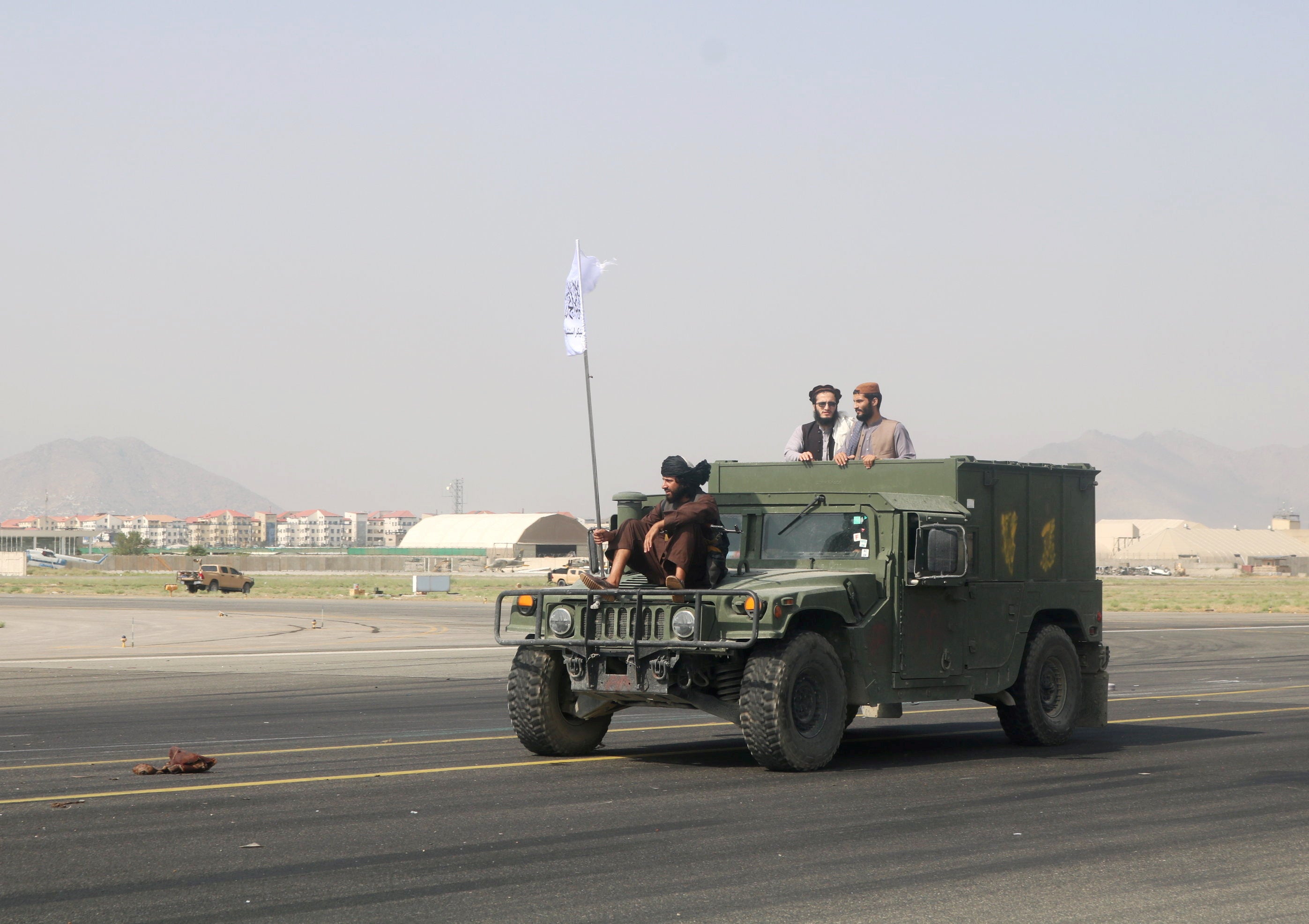 Taliban forces use an armoured vehicle to patrol along the runway at Kabul airport