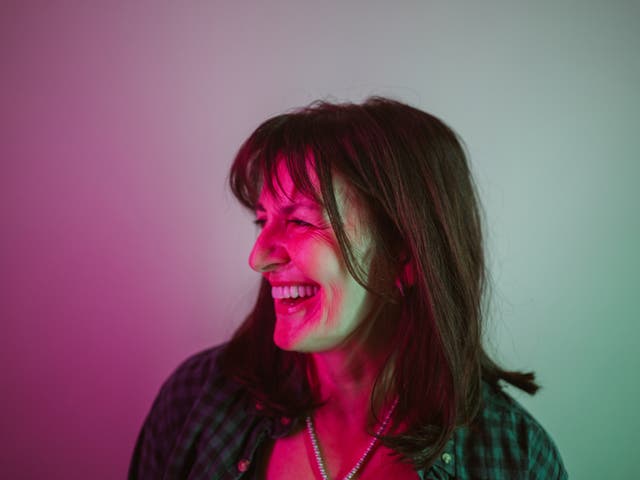 <p>A woman smiles under neon lights</p>