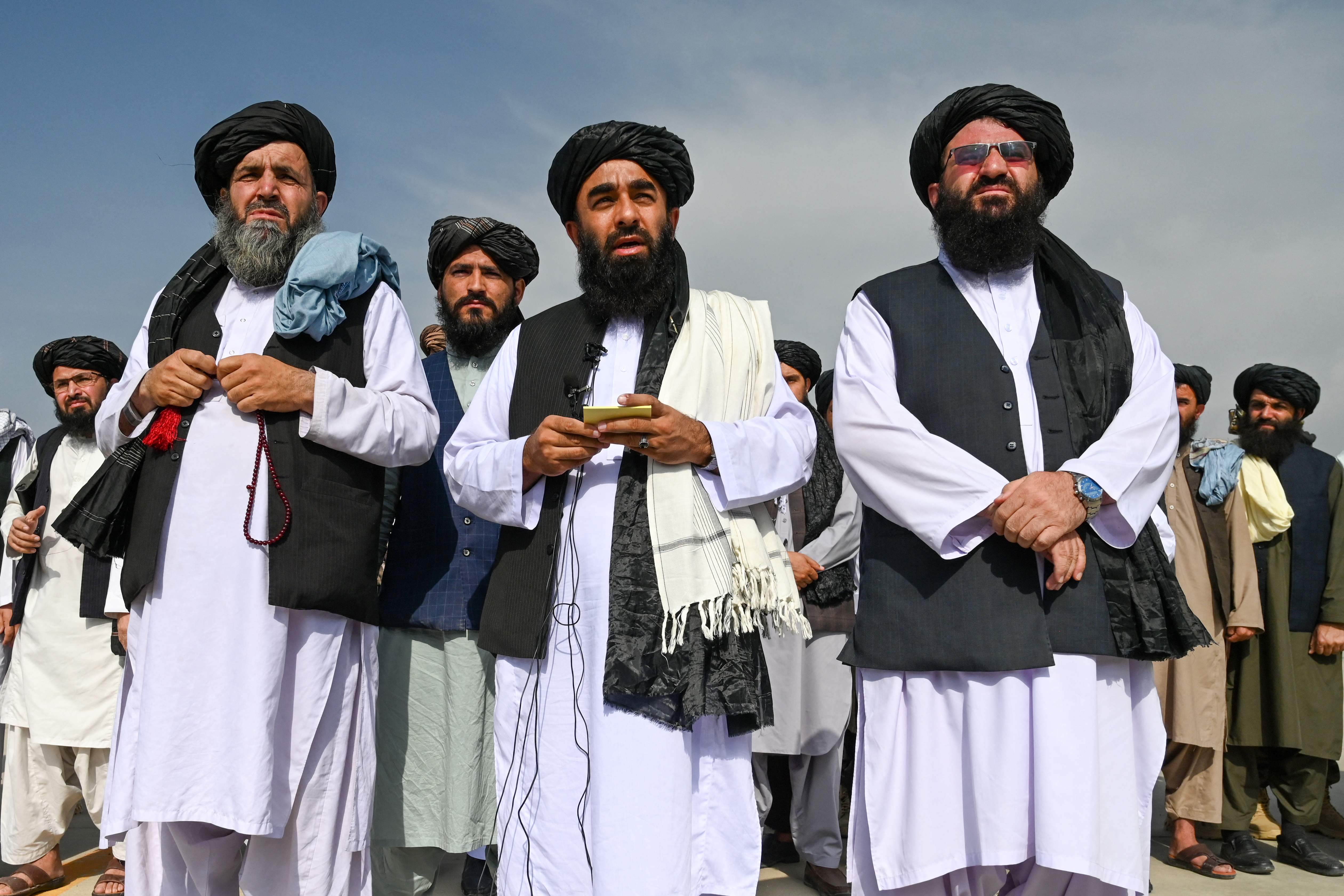 Taliban spokesman Zabihullah Mujahid (C) briefs media at the Kabul airport