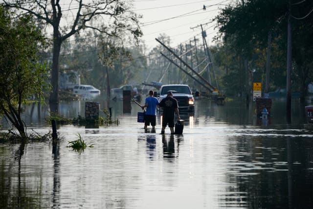 <p>People walk up a street flooded in the aftermath of Hurricane Ida on 1 September in Jean Lafitte, Louisiana </p>