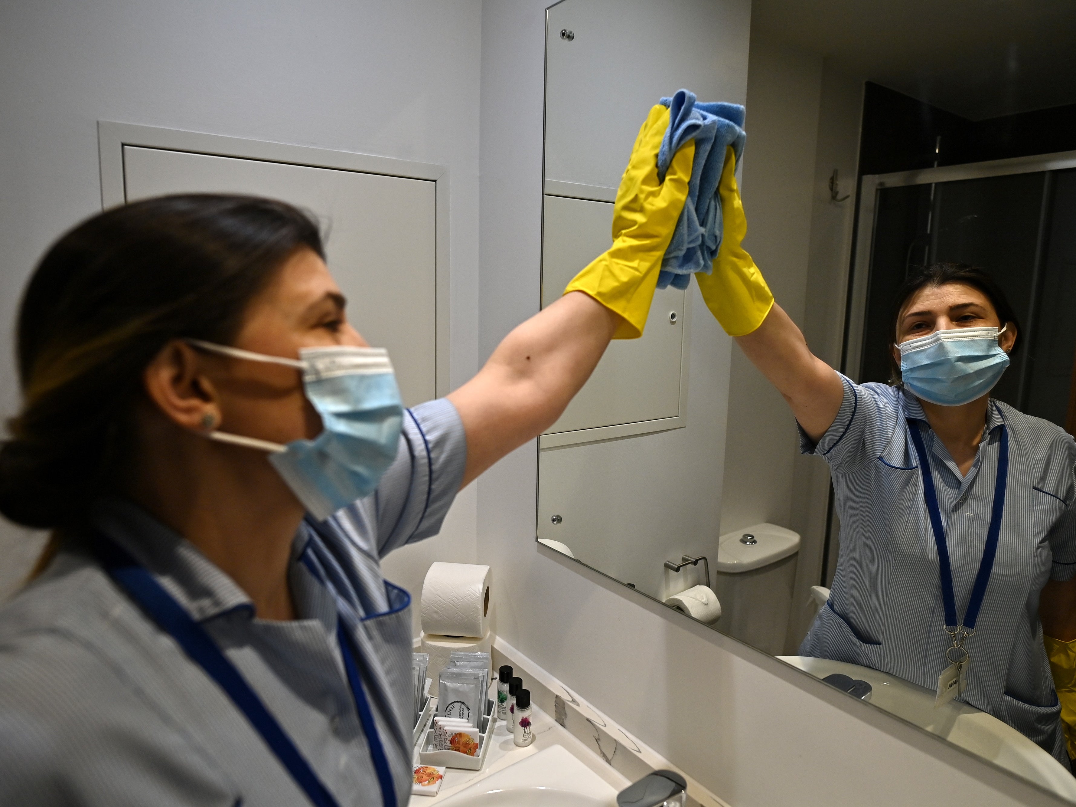 <p>A staff member cleans surfaces at a hotel near Heathrow Airport</p>