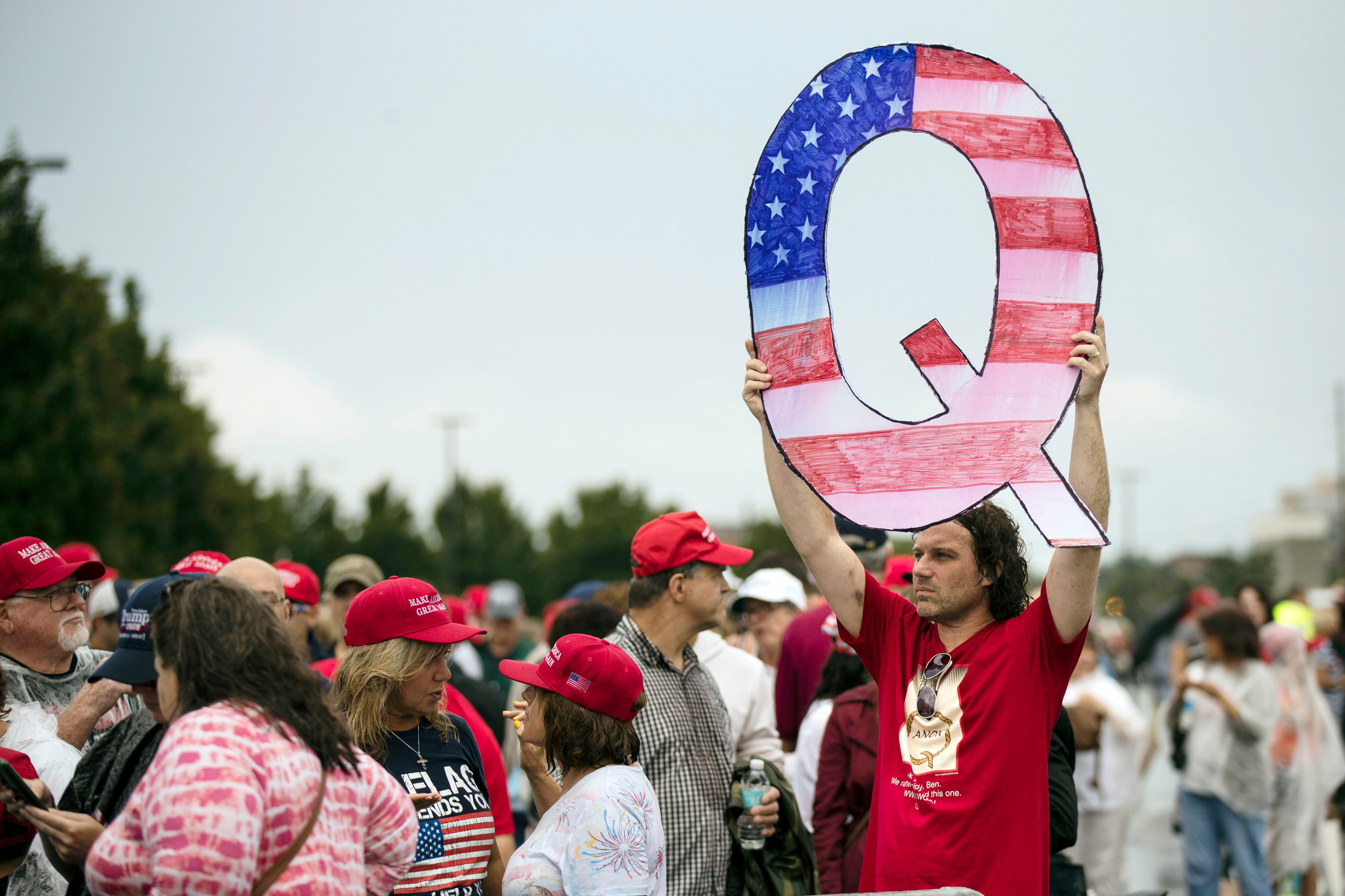 File A protester holds a Q sign as he waits in line with others to enter a campaign rally with President Donald Trump in Wilkes