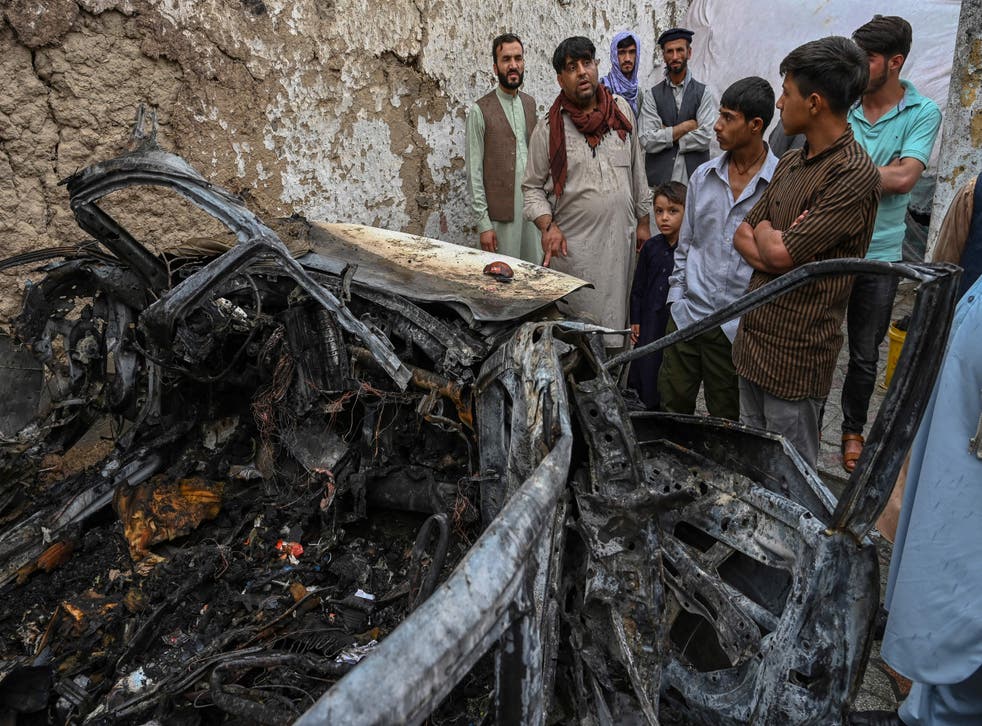<p>Afghan residents and family members of the victims gather next to a damaged vehicle inside a house, day after a US drone airstrike in Kabul on 30 August, 2021. </p>