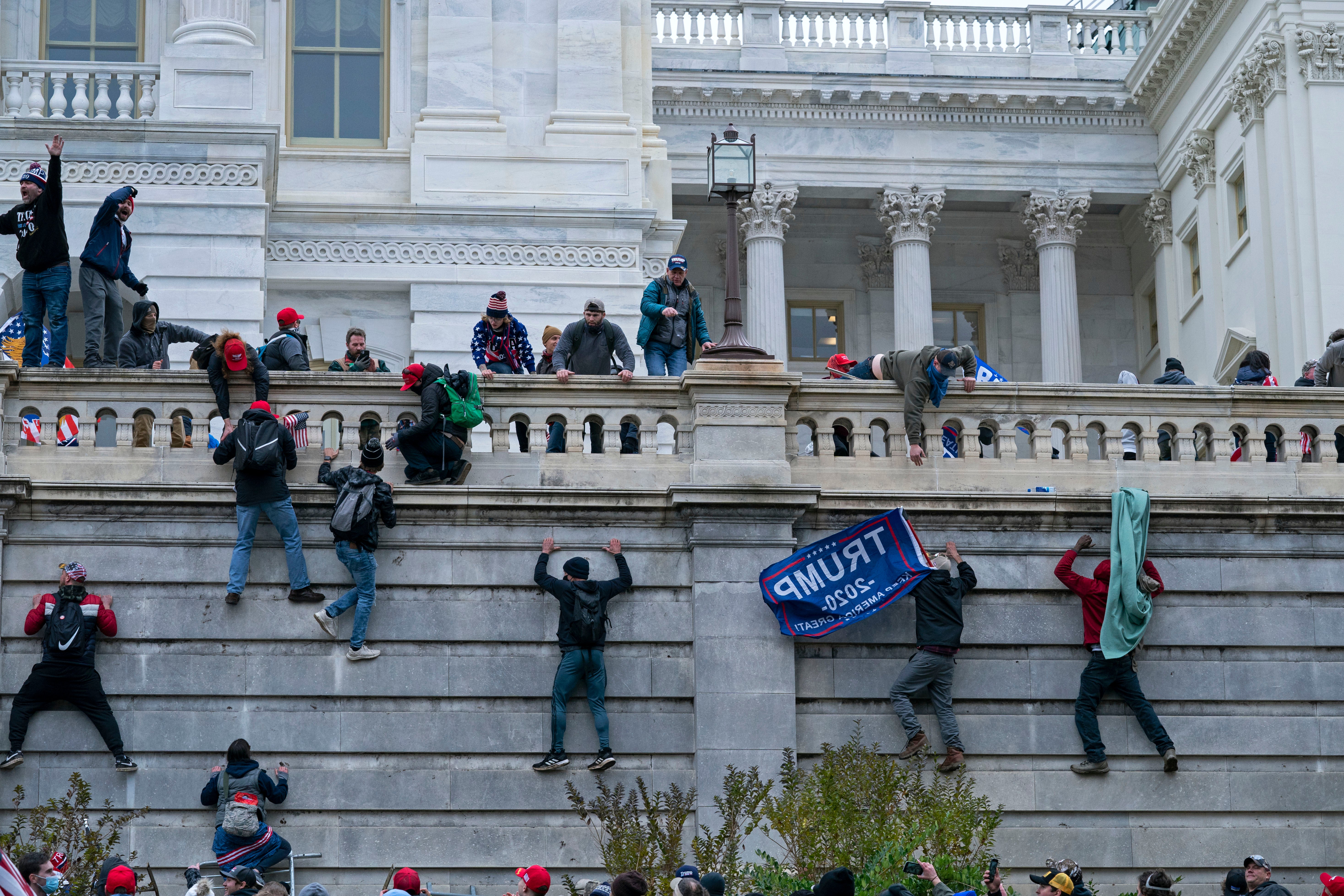 Rioters climb the west wall of the the US Capitol in Washington on 6 January