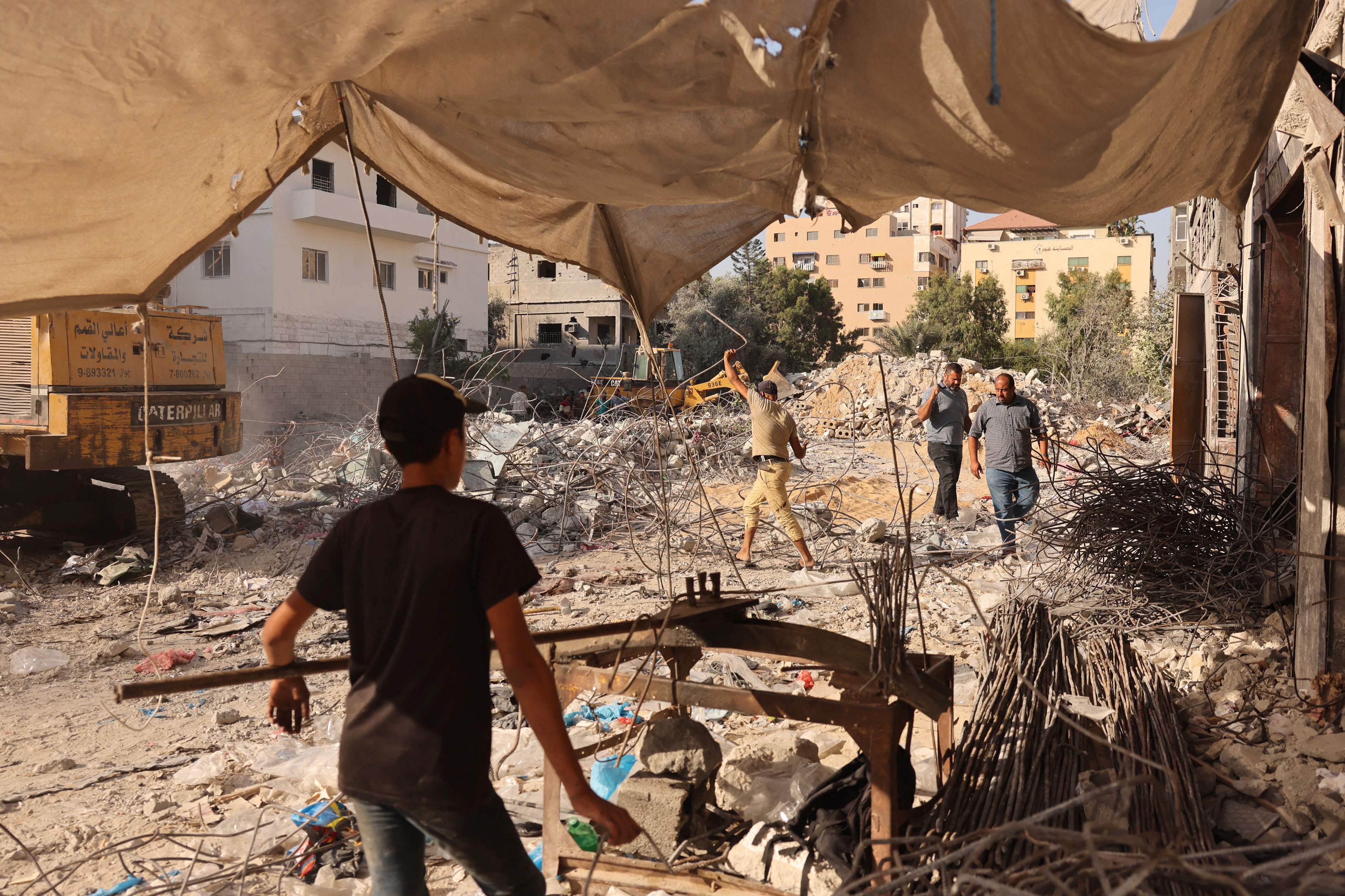 Palestinian workers straighten steel bars extracted from the ruins of buildings destroyed in the last round of Israeli-Hamas fighting