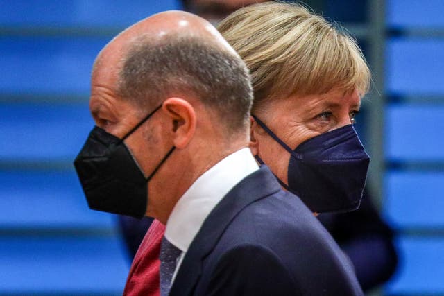 <p>The German minister of finance, Olaf Scholz (left), passes by the German chancellor, Angela Merkel, at the weekly government cabinet meeting in Berlin</p>