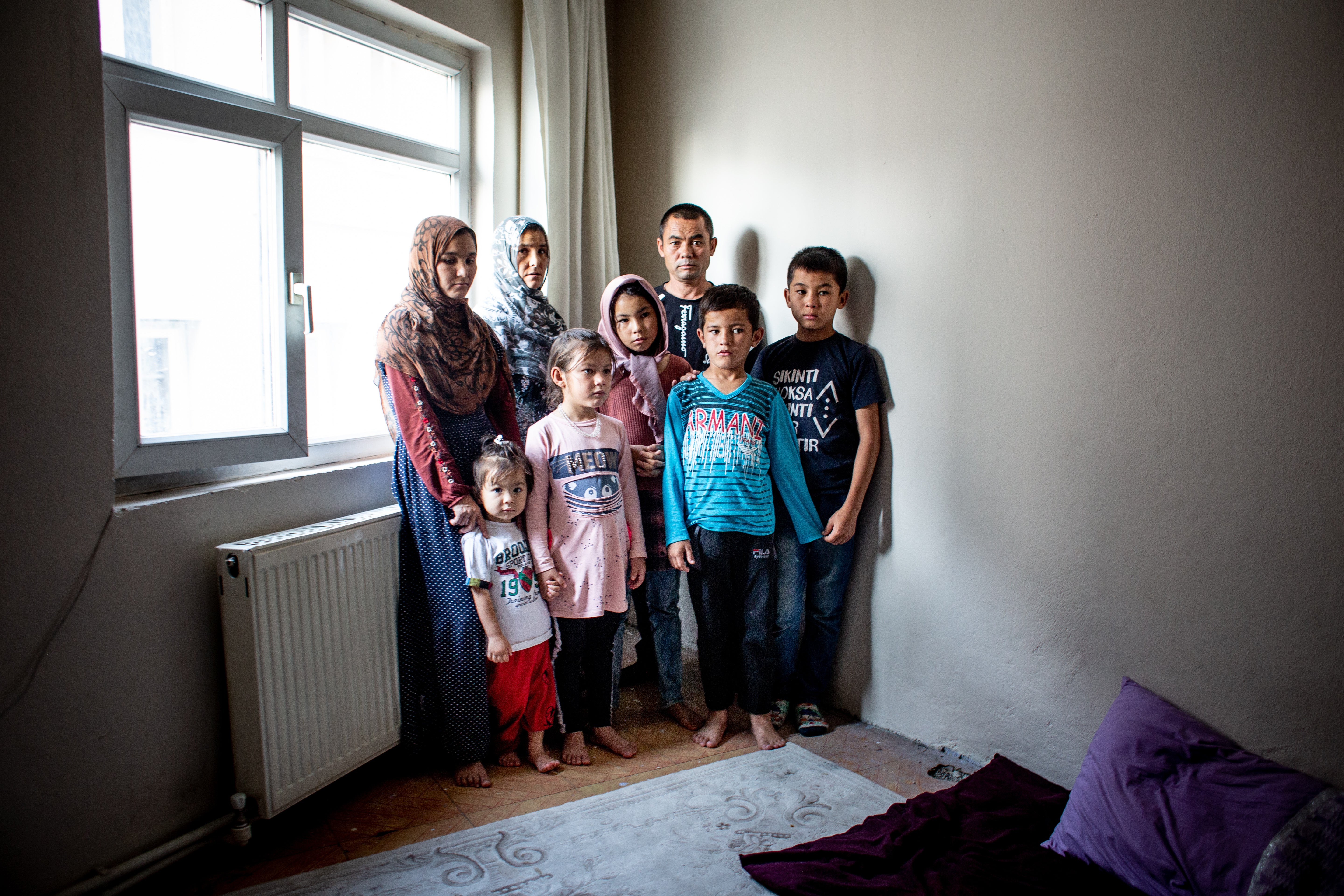 Abdul Kareem Buri, 35, his wife Bibigol, his late brother’s pregnant wife Nasrin-gol, and some of their children pose for a portrait in the Van apartment they have been staying in for nearly a month