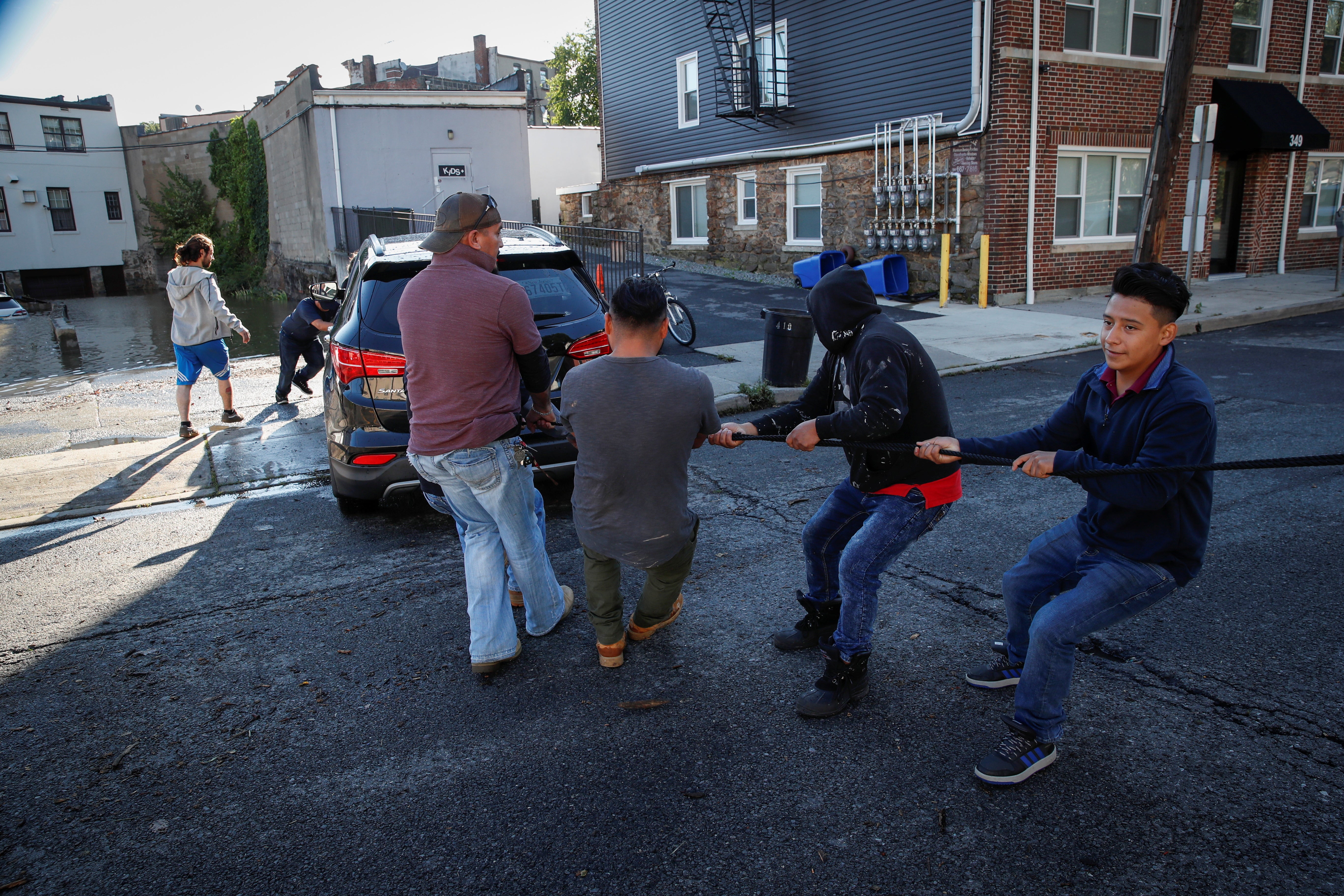 Locals pull a disabled vehicle from floodwaters after the remnants of Tropical Storm Ida brought drenching rain, flash floods and tornadoes to parts of the northeast in Mamaroneck, New York