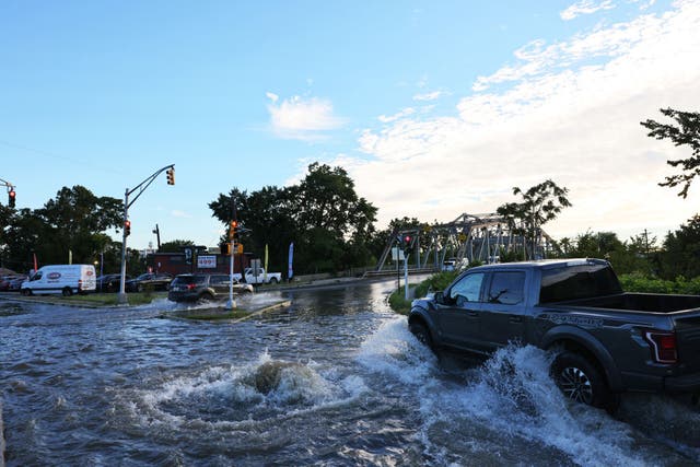 <p>Vehicles drive through flooded River Drive as water gushes out of a manhole on 2nd September in Passaic City. Governor Phil Murphy declared a state of emergency as Tropical Storm Ida caused flooding and power outages throughout New Jersey </p>