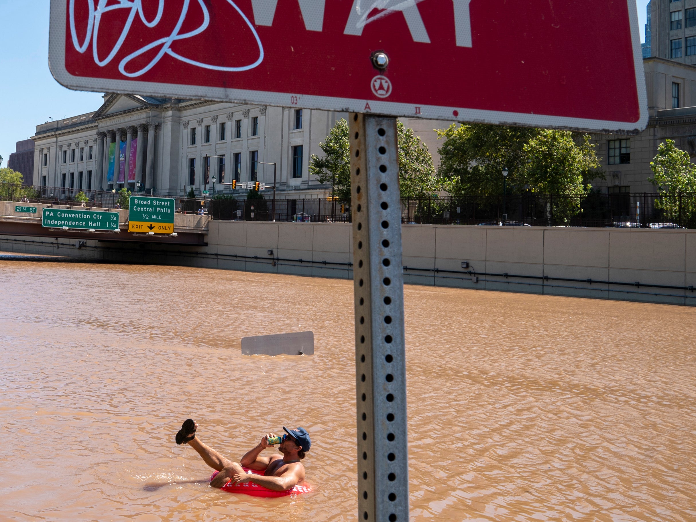 pAustin Ferdock drinks a beer while floating in floodwater that continues to rise over the submerged Vine Street Expressway/p