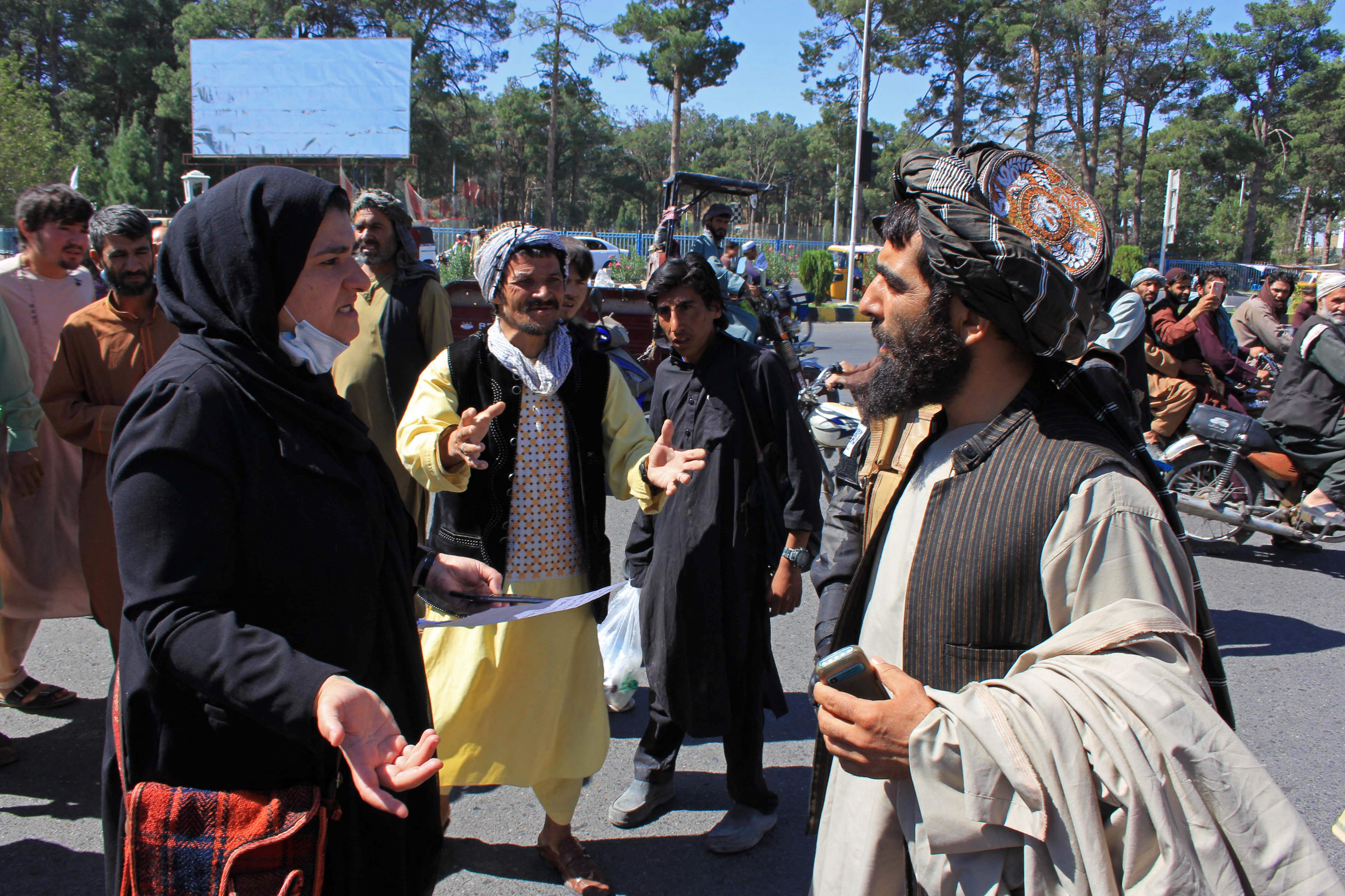 An Afghan woman protester (3L) speaks with a member (R) of the Taliban during a protest in Herat