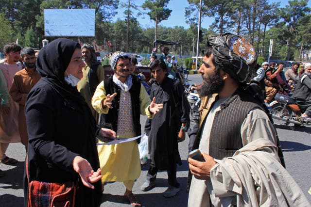 <p>An Afghan woman protester speaks with a member of the Taliban</p>