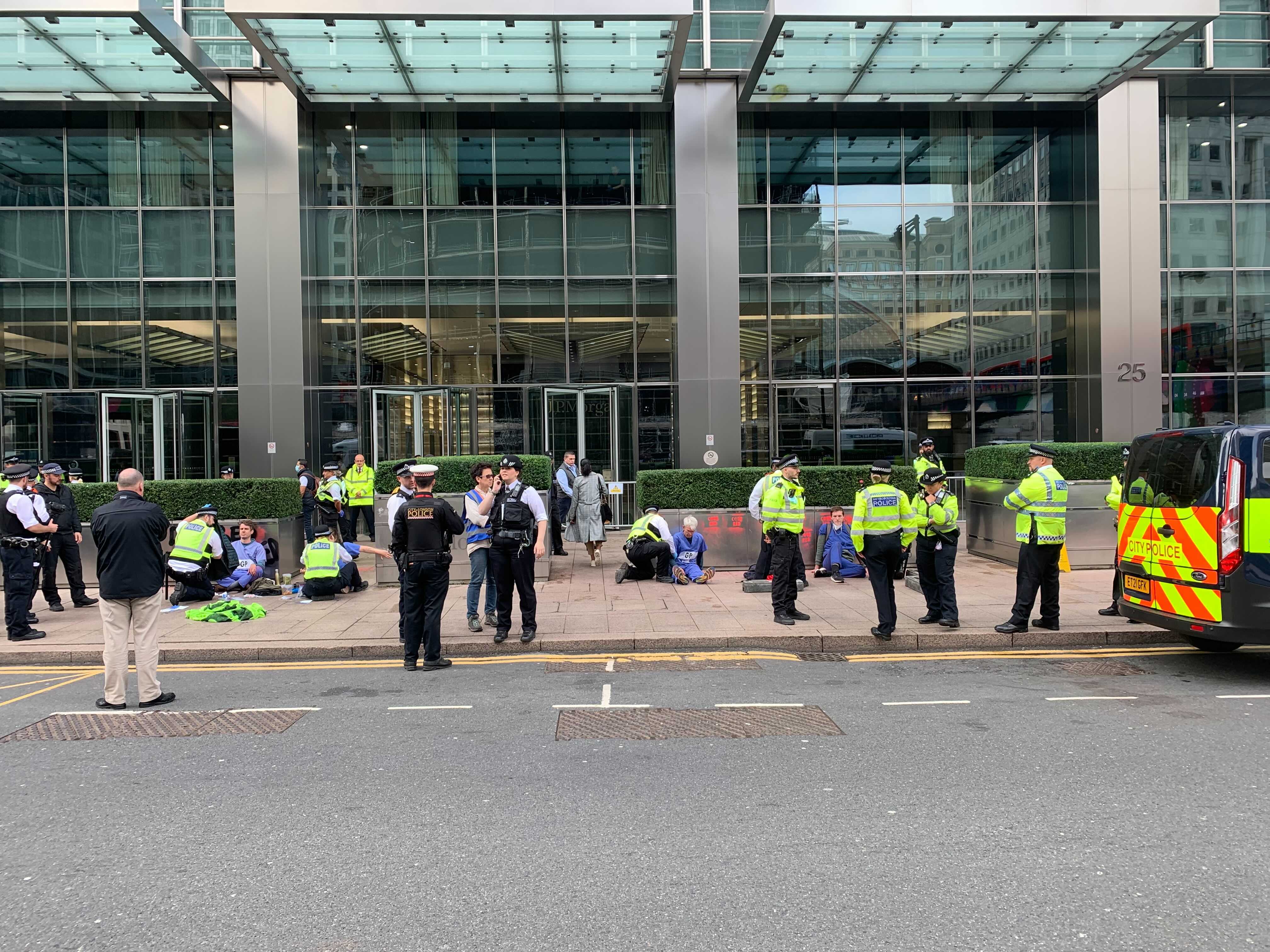Protesters with their hands stuck to the pavement outside JP Morgan