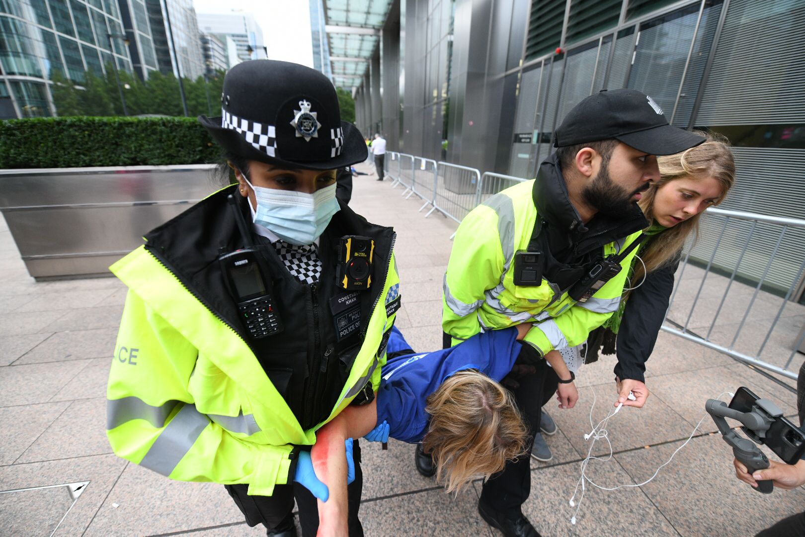 A Met Police officer and a Canary Wharf security guard carry a doctor away by her arms and legs after she refused to move herself