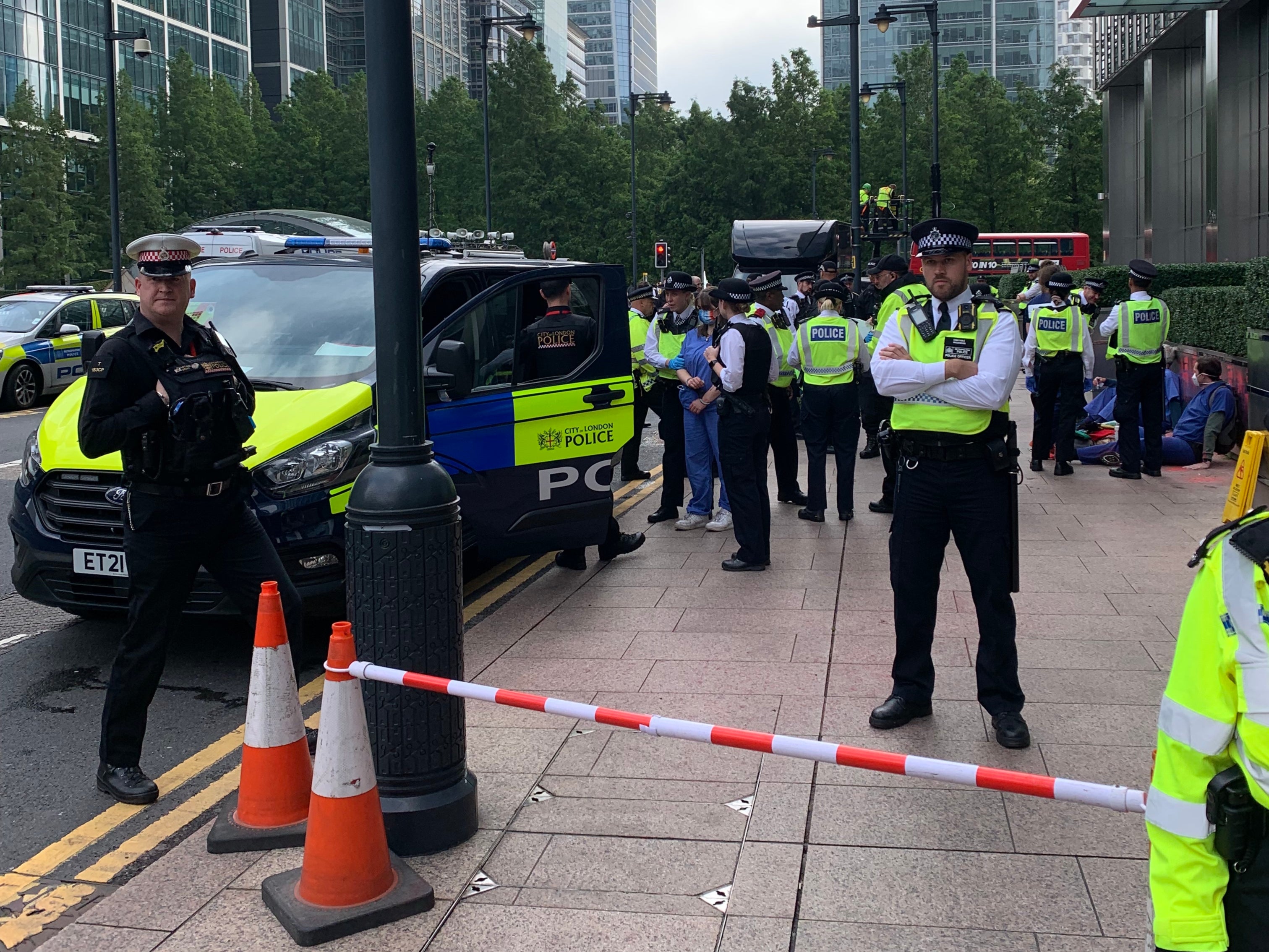 A medical student who glued herself to JP Morgan’s planter is handcuffed and loaded into a police van