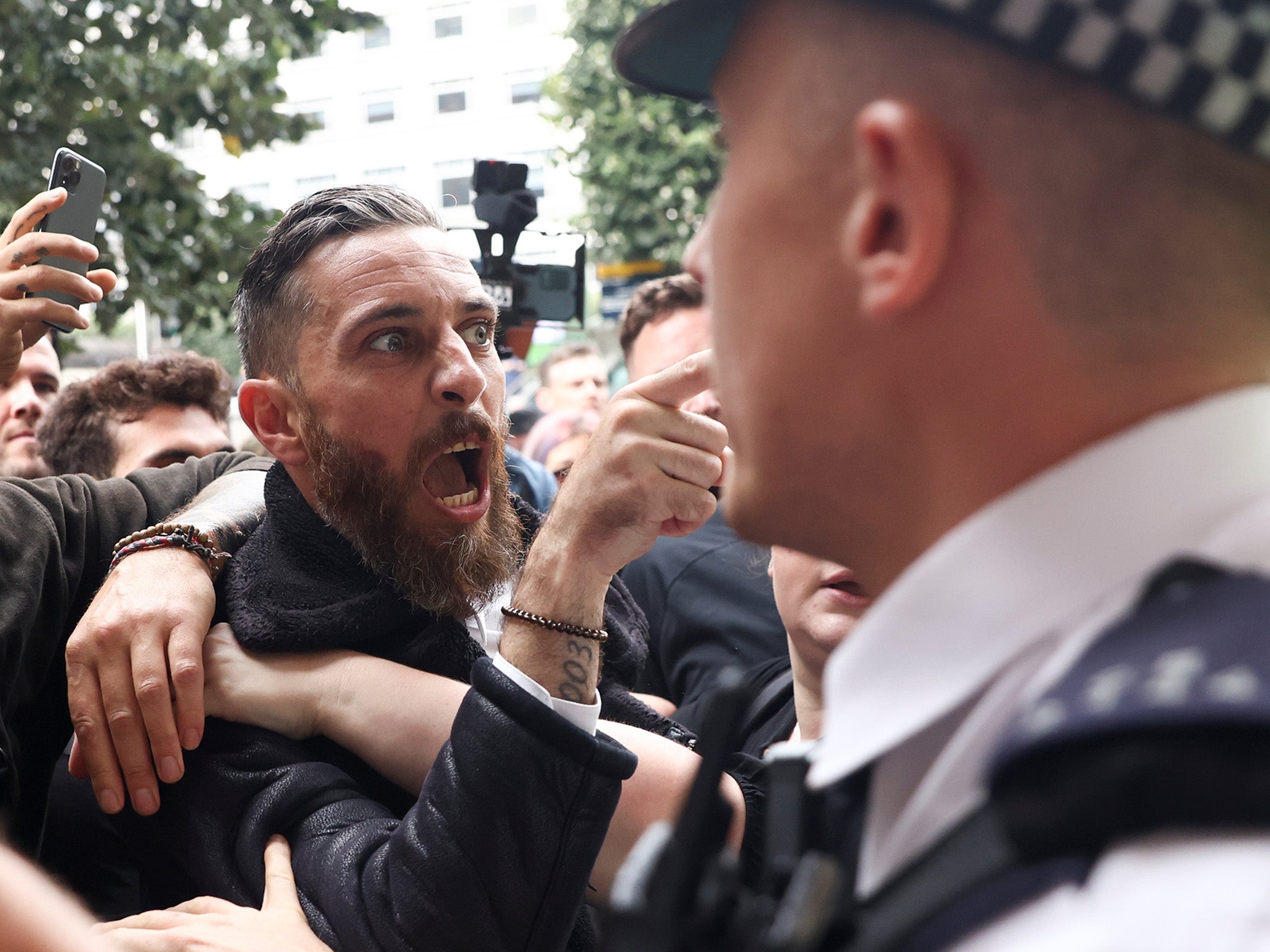 <p>Police officers stand guard as members of the Official Voice group protest in Canary Wharf </p>