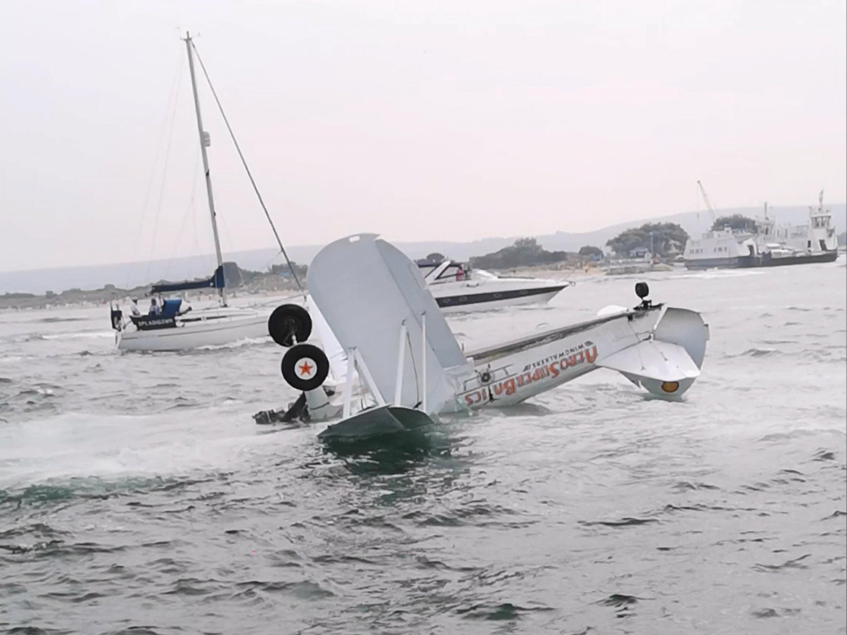 Eyewitnesses saw the two-seat biplane crash down in Poole Harbour, near Bournemouth, on Saturday afternoon