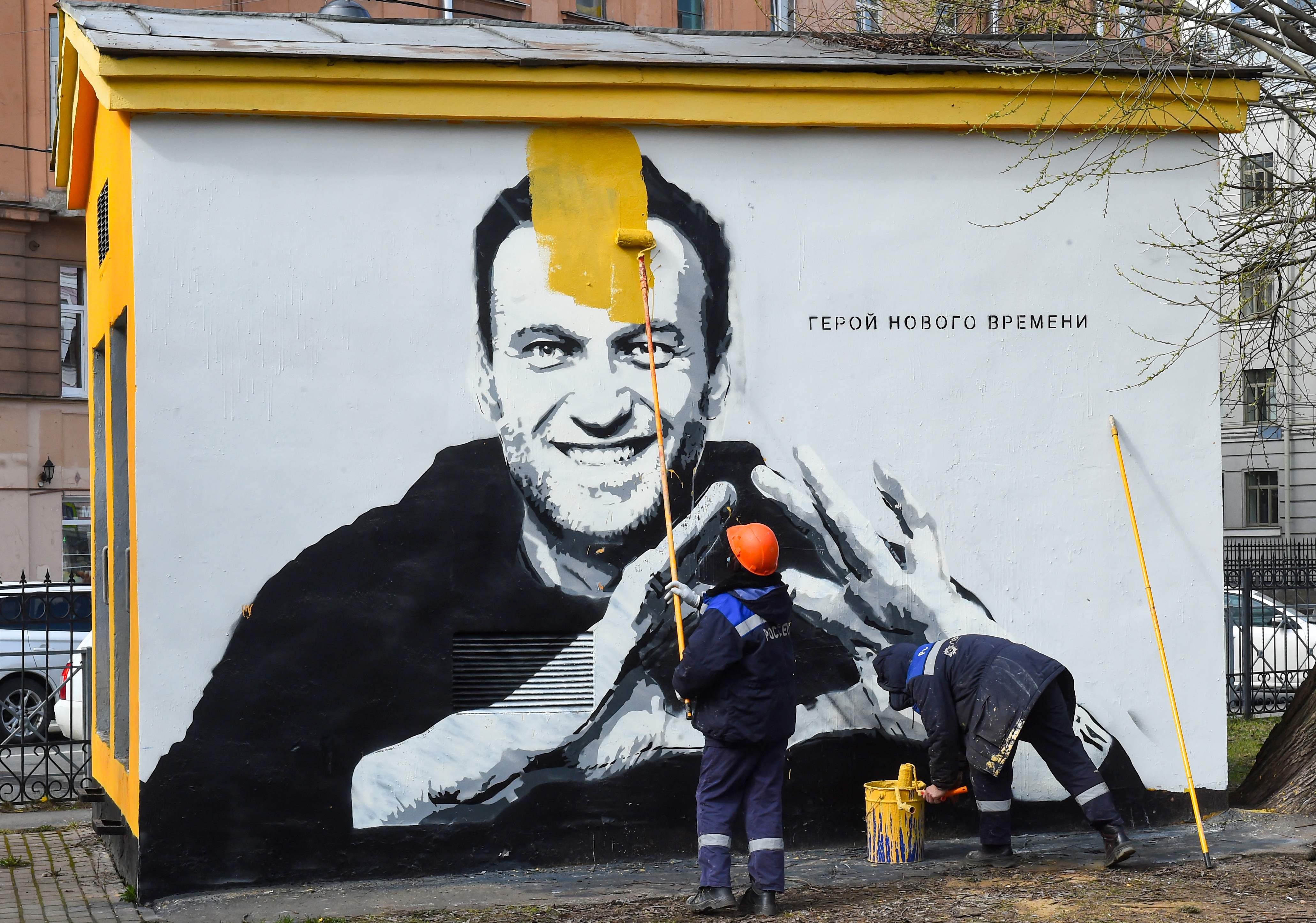 a worker paints over graffiti of jailed Kremlin critic Alexei Navalny in Saint Petersburg. The inscription reads: "The hero of the new times".