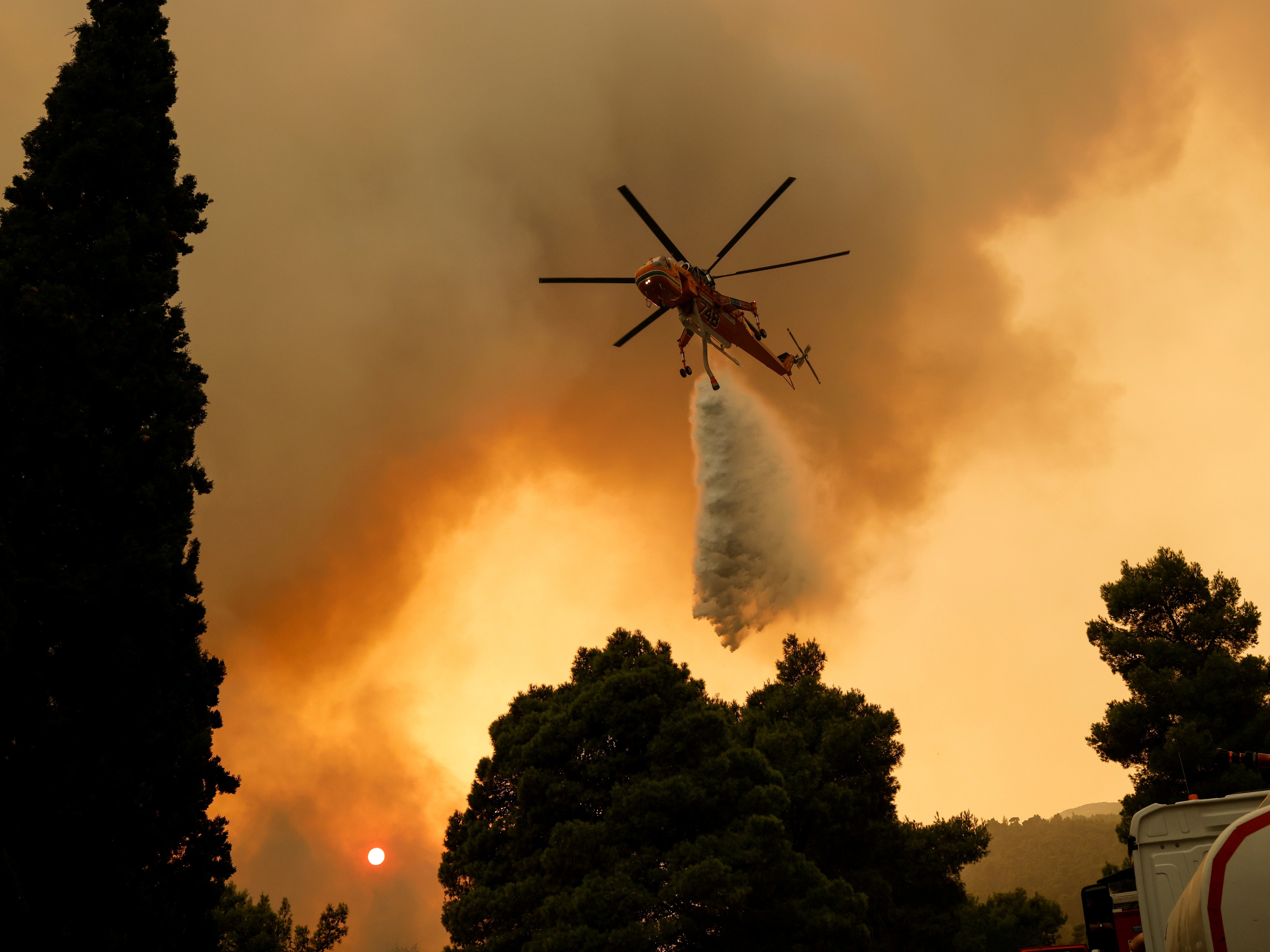 A helicopter makes a water drop as a wildfire burns in Vilia, Greece, in August