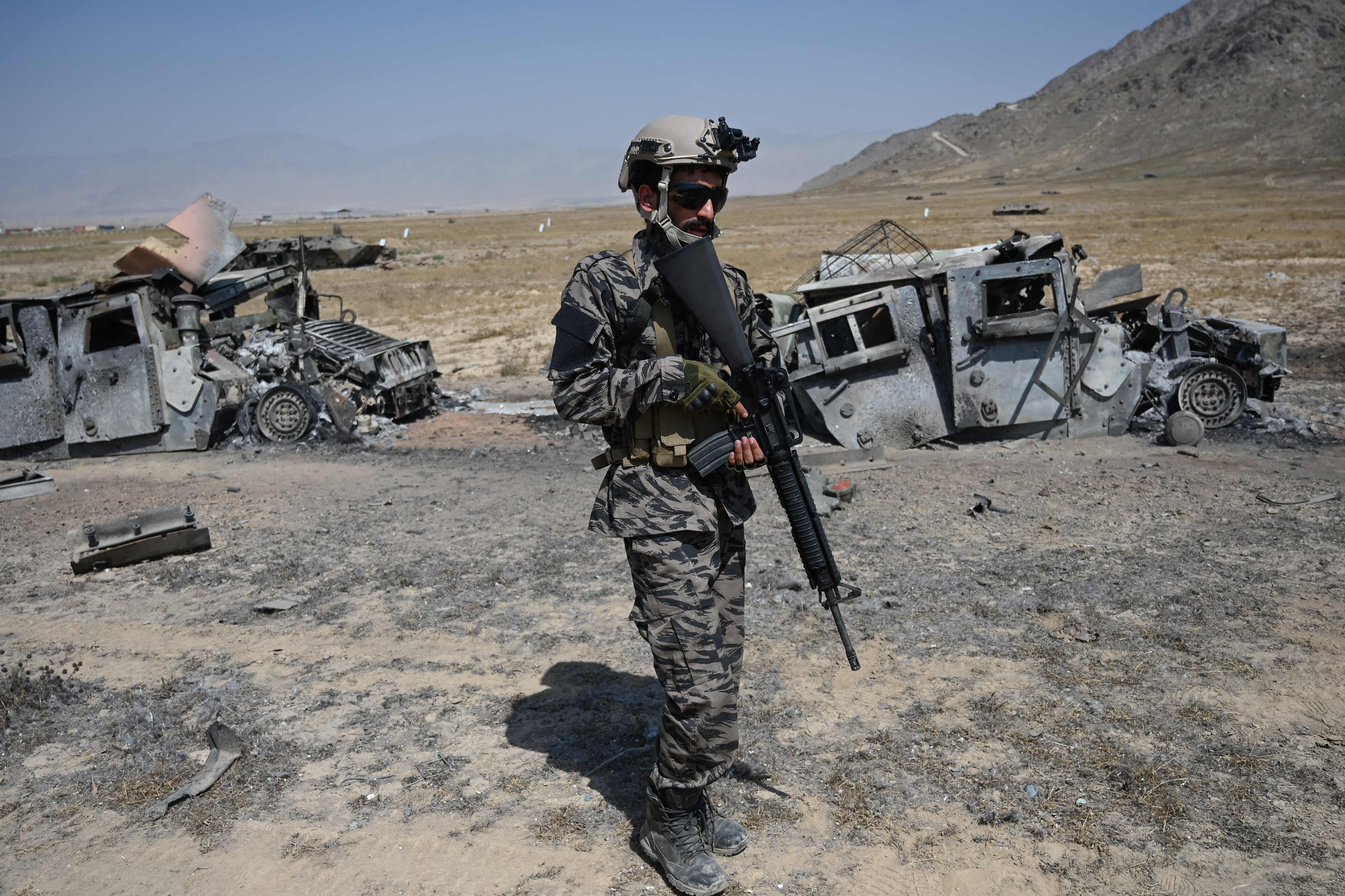 A member of the Taliban Badri 313 military unit stands besides damaged vehicles near Kabul