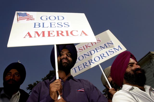 <p>Sikh men carry patriotic placards at a community service to remember victims of terrorist attacks on  10 October, 2001 in Santa Ana</p>