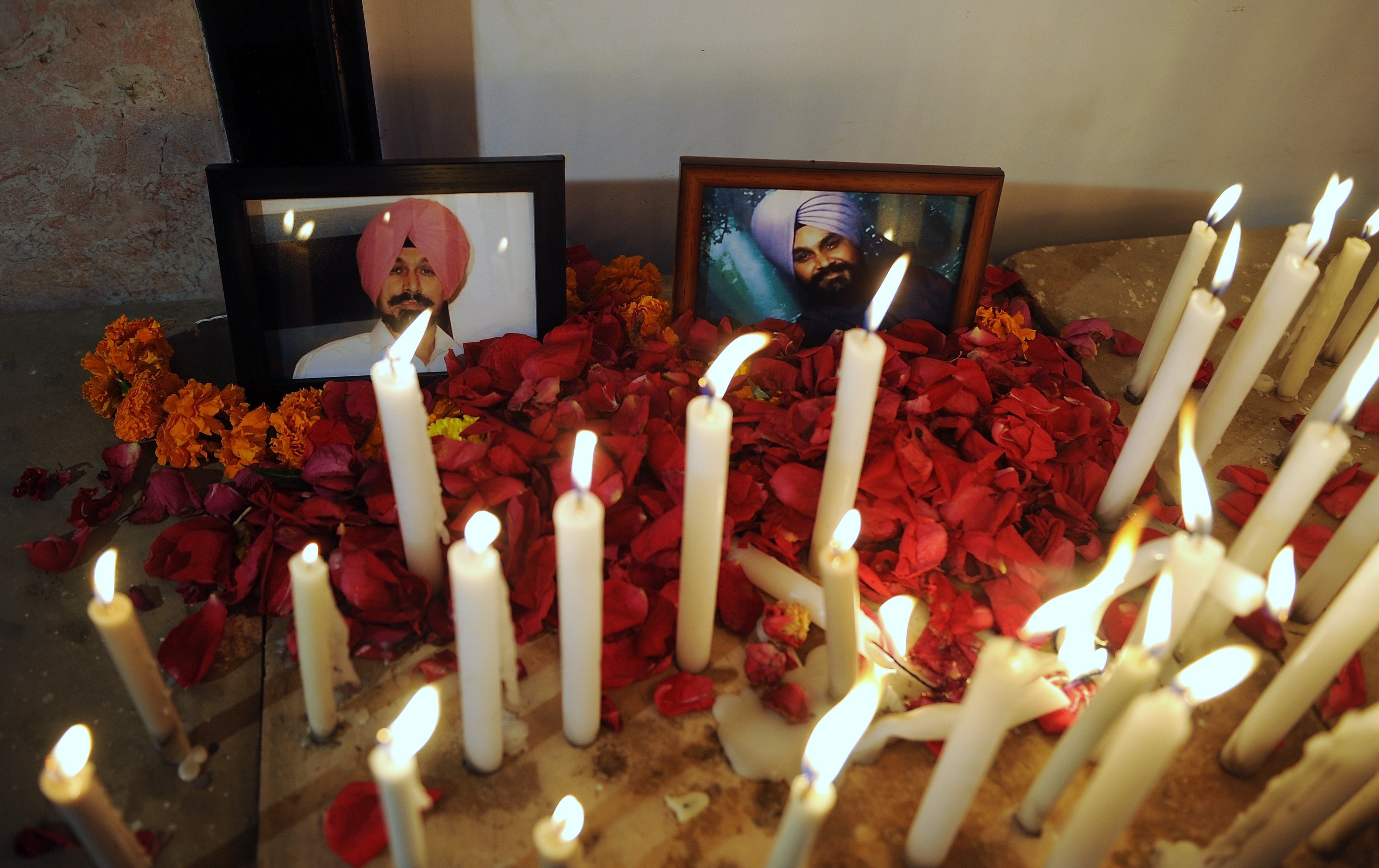 Indian Sikhs place flower petals and candles near pictures of those killed at a Sikh Temple shooting in the United States during a vigil in Mumbai on August 8, 2012. A suspected gunman, 40-year-old Wade Michael Page, allegedly killed six people at a Sikh temple in the United States on August 5, and was shot to death by police at the scene.