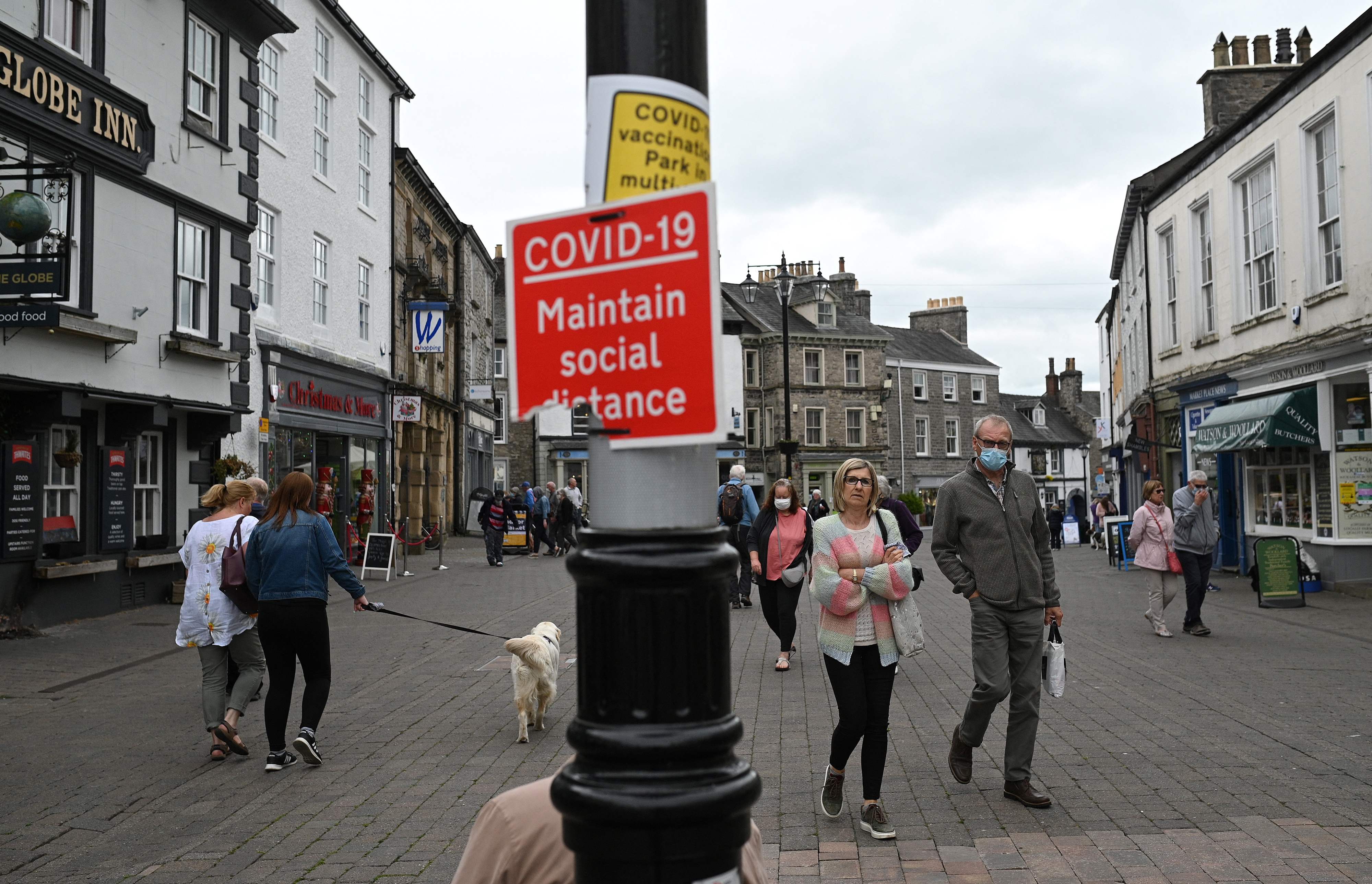 Members of the public walk past shops in Kendal in Cumbria, north-west England